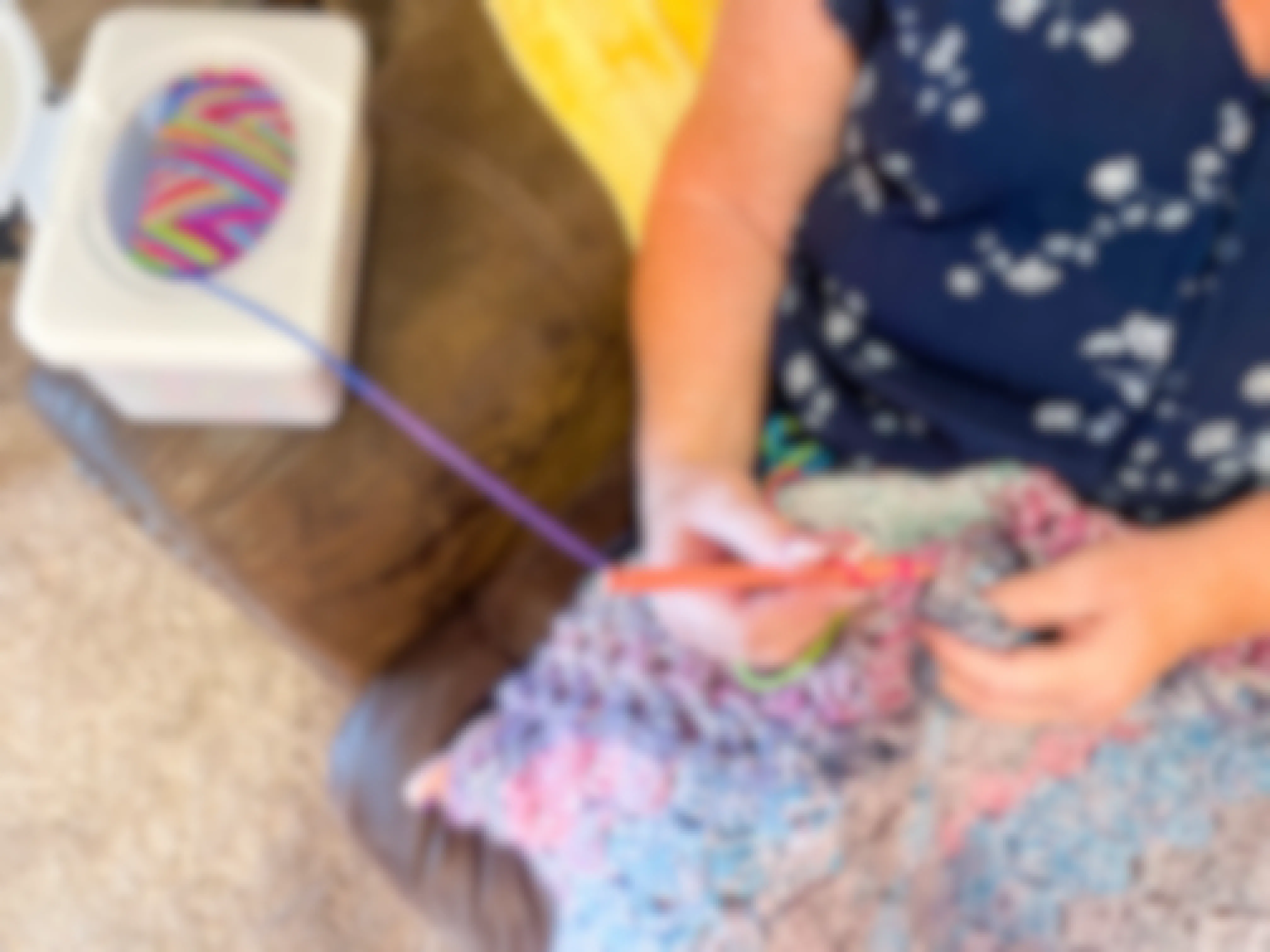 a baby wipe container being reused as a yarn holder with a woman croceting 