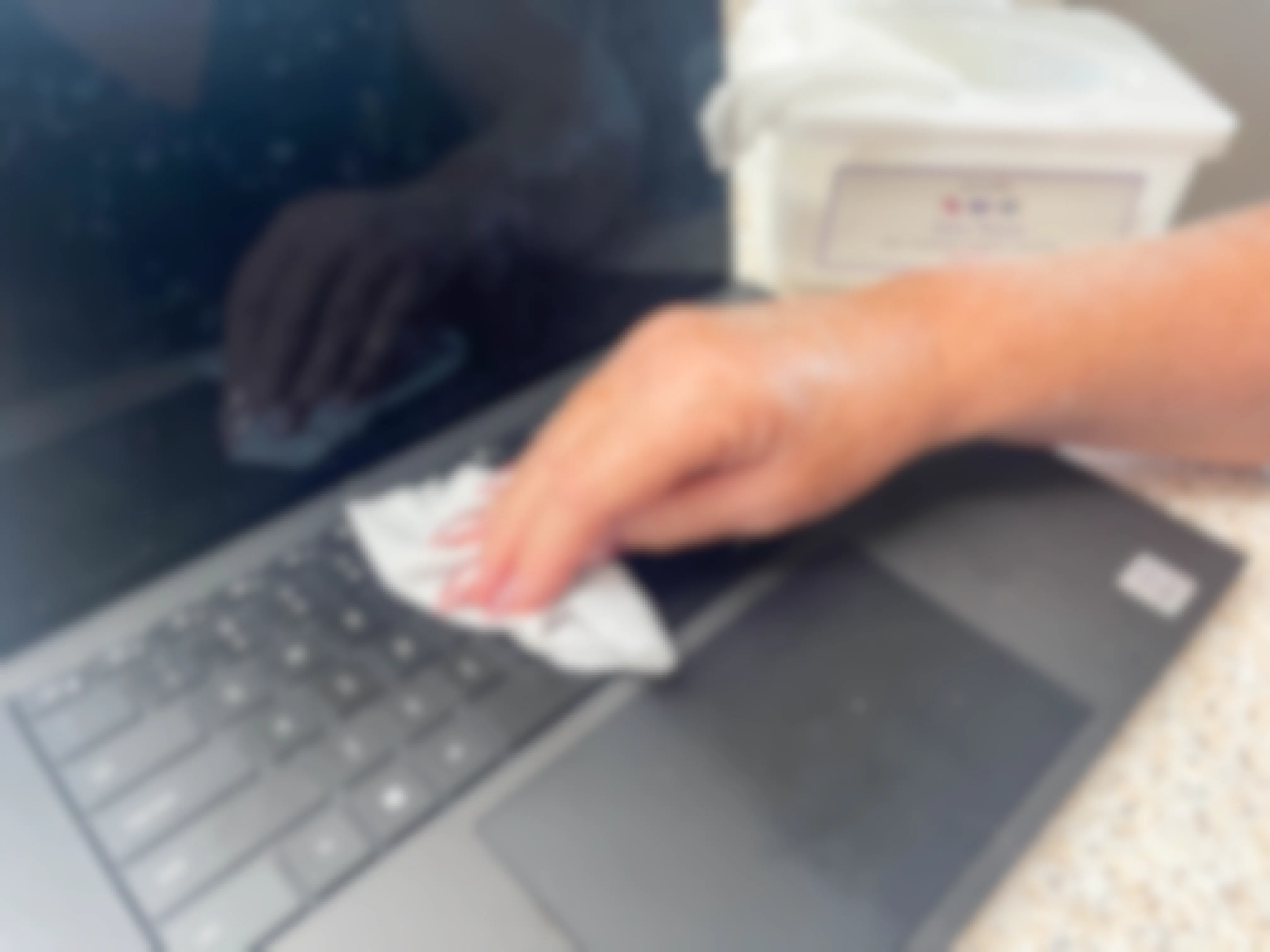 a woman using a baby wipe to wipe up dust on keyboard