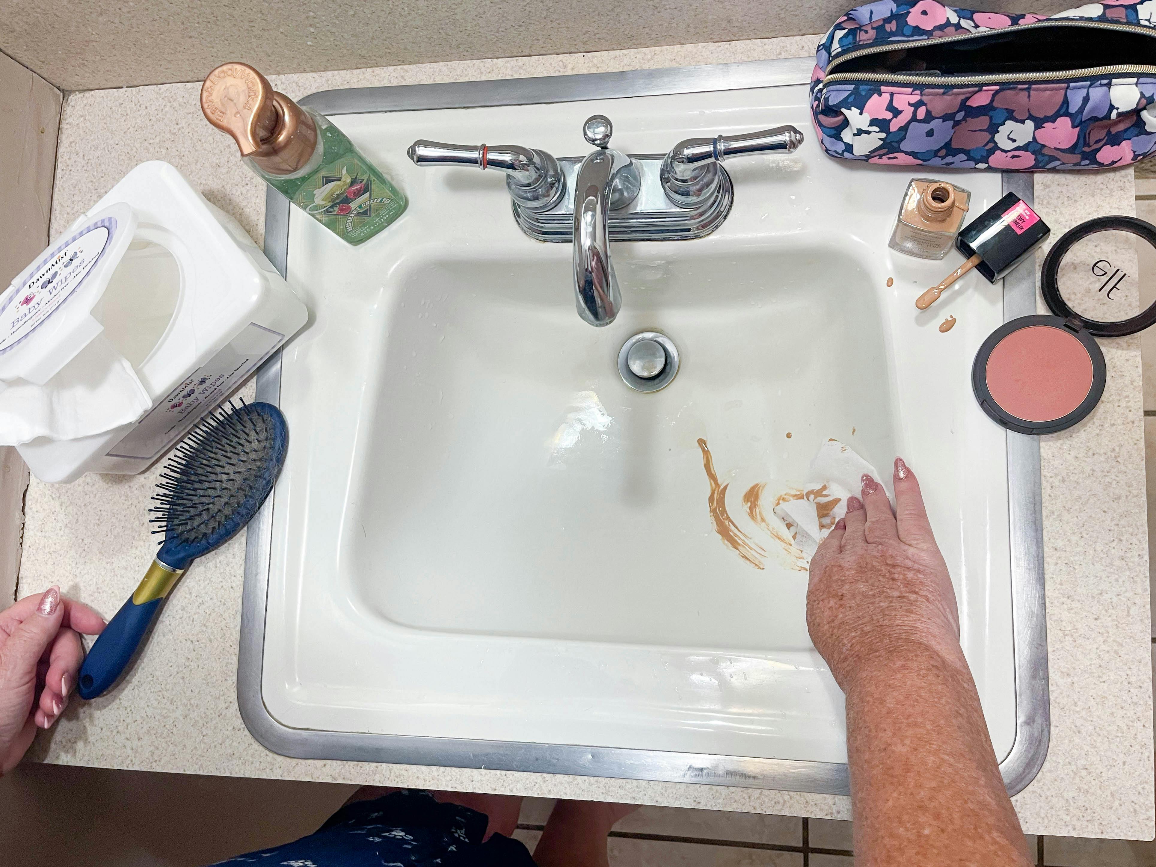 a woman using a baby wipe to wipe up a makeup spill in sink