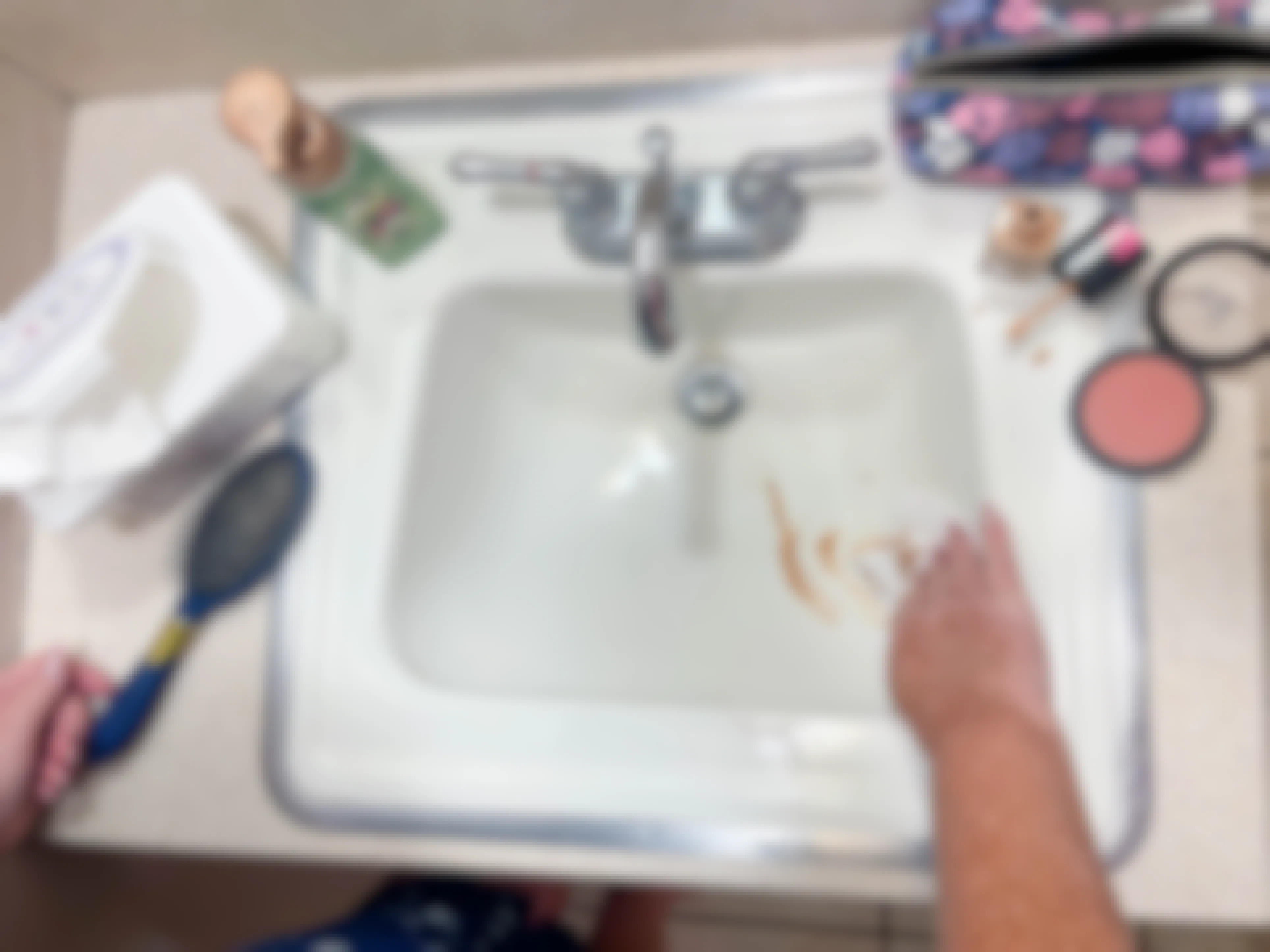 a woman using a baby wipe to wipe up a makeup spill in sink 