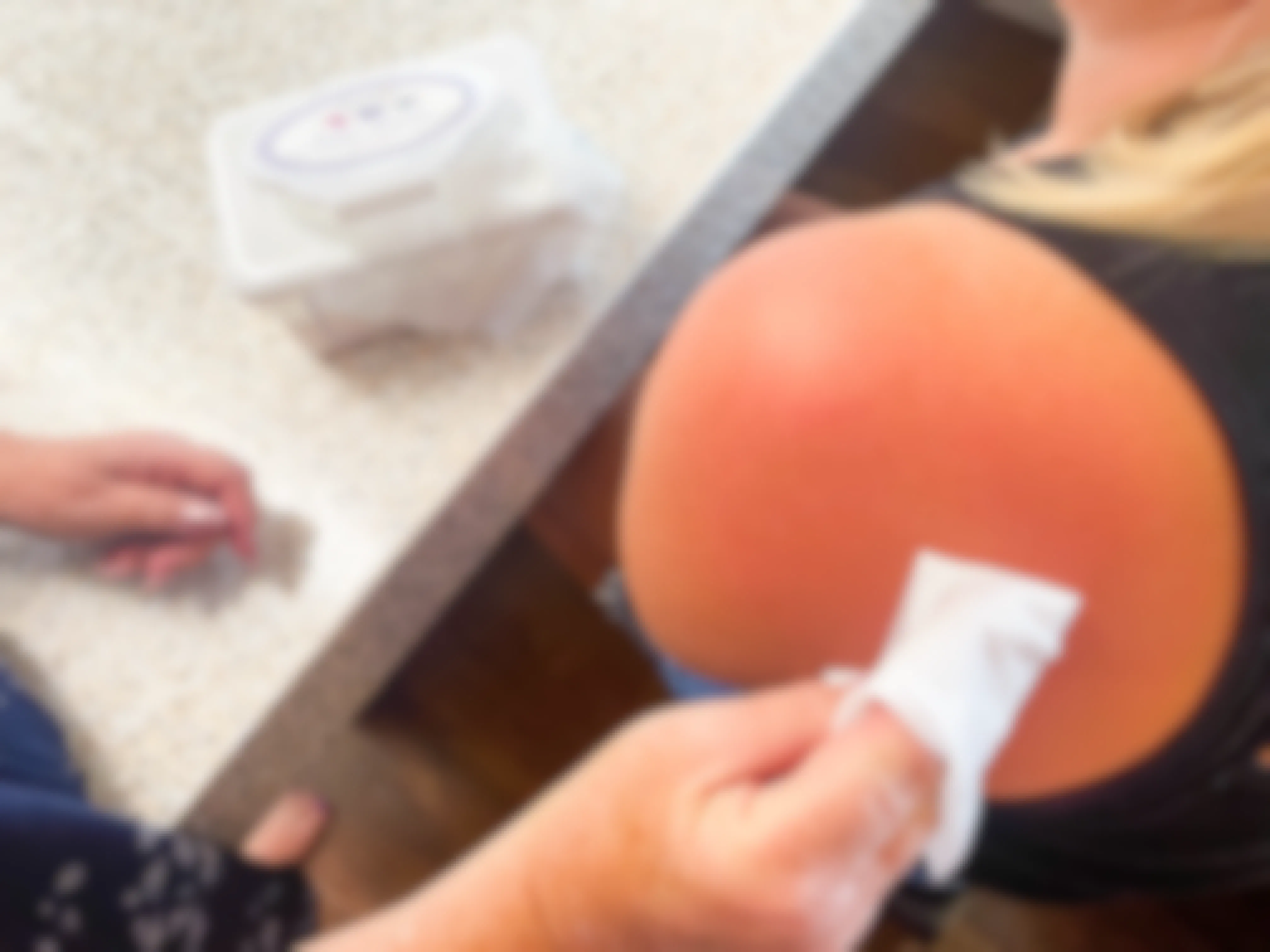 a woman using a baby wipe to wipe a wipe on a sunburn 