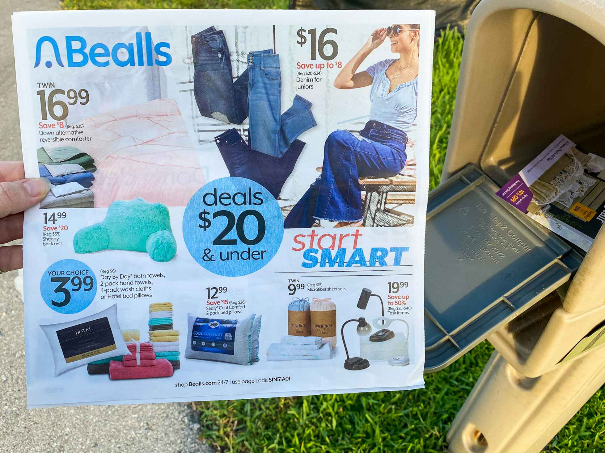 A person's hand taking a Bealls mailer from their mailbox.