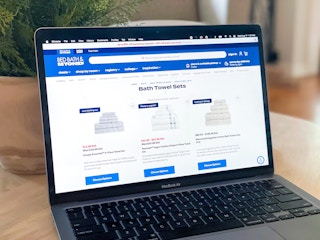 a macbook air showing the bath towels page open on the bed bath and beyond website
