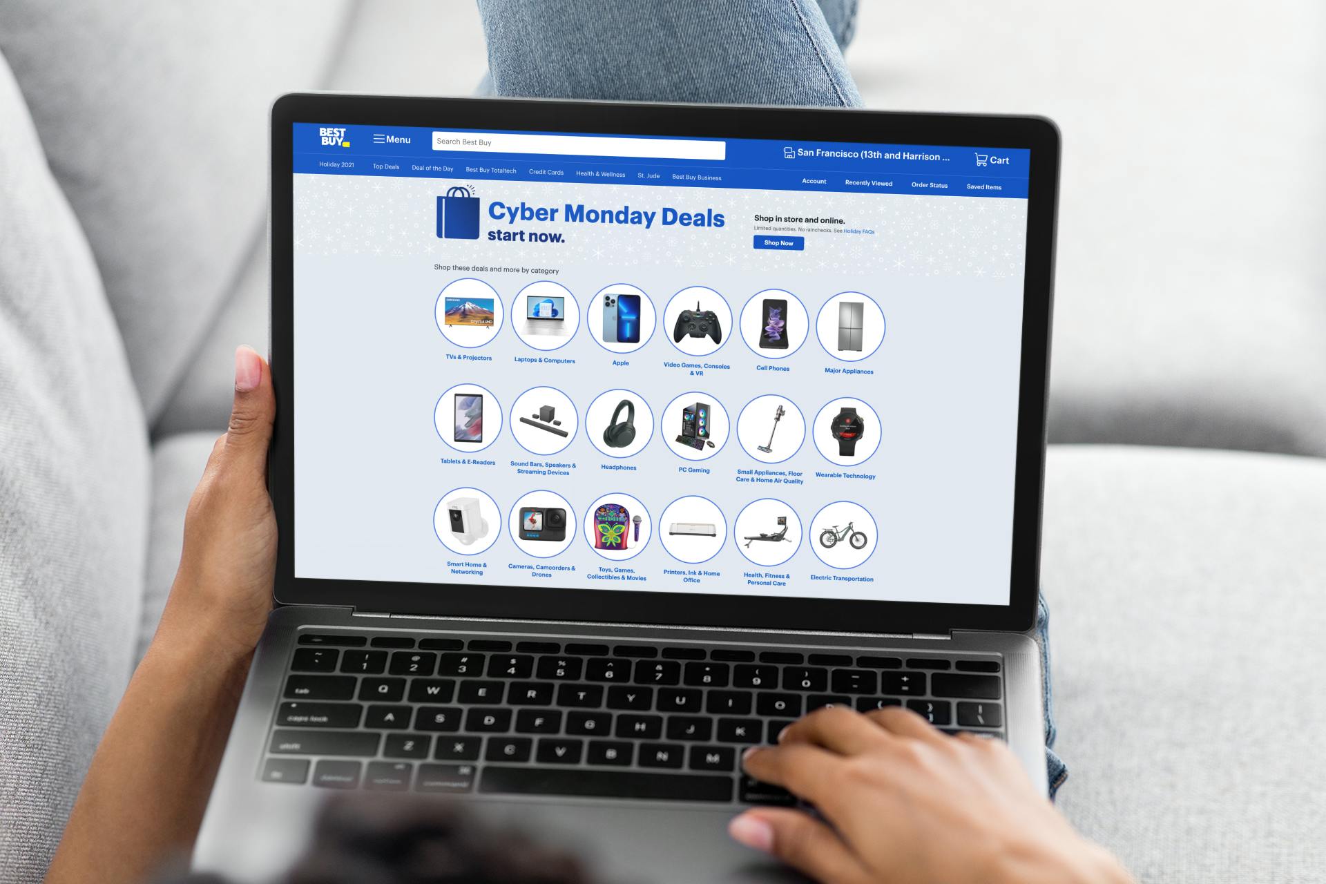 A woman lying on the couch with her laptop in her lap open to Best Buy's online Cyber Monday deals