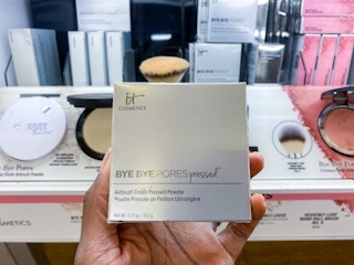 someone holding an it cosmetics bye bye pores pressed powder box