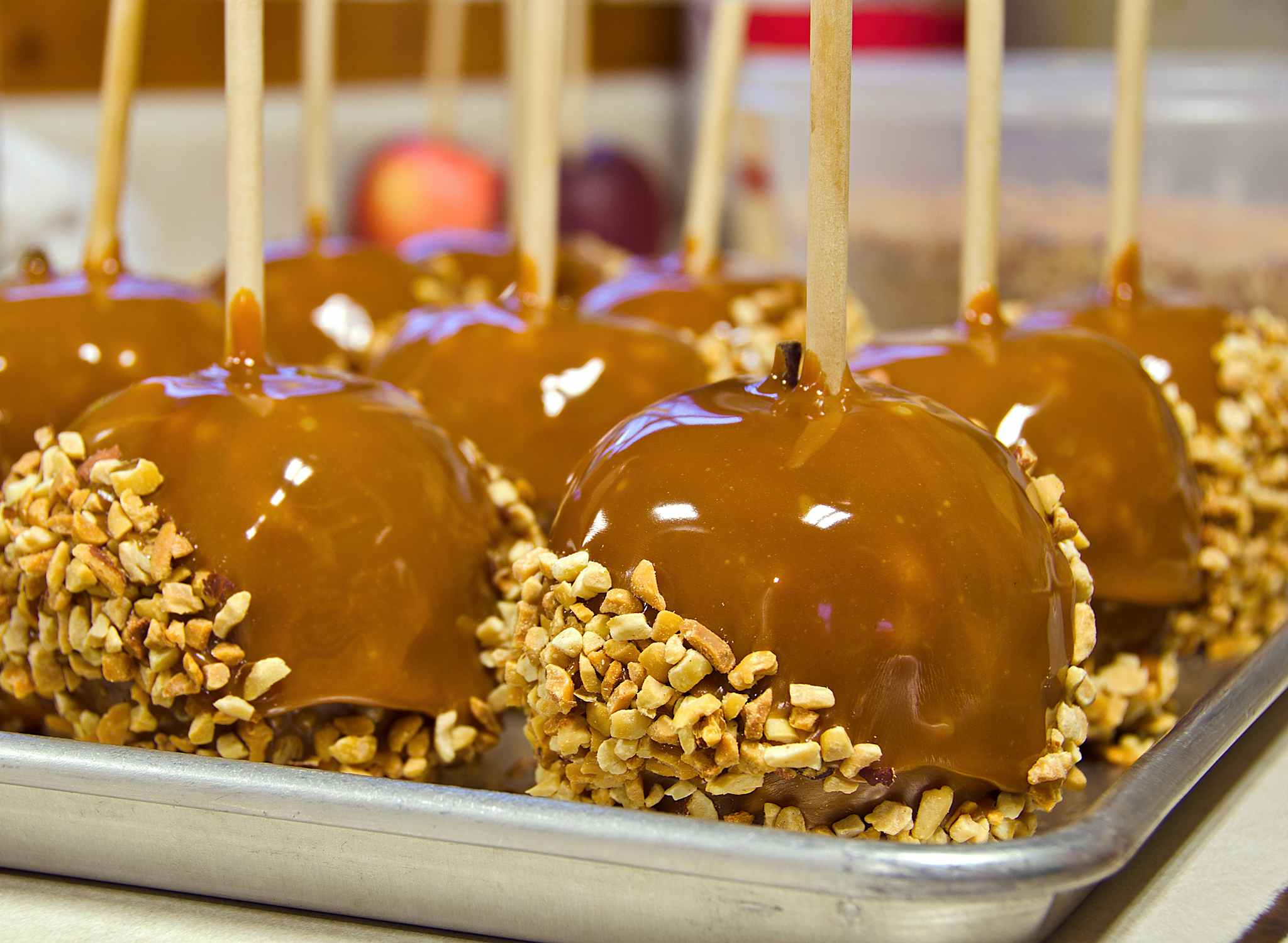 caramel apples dipped in nuts on baking sheet