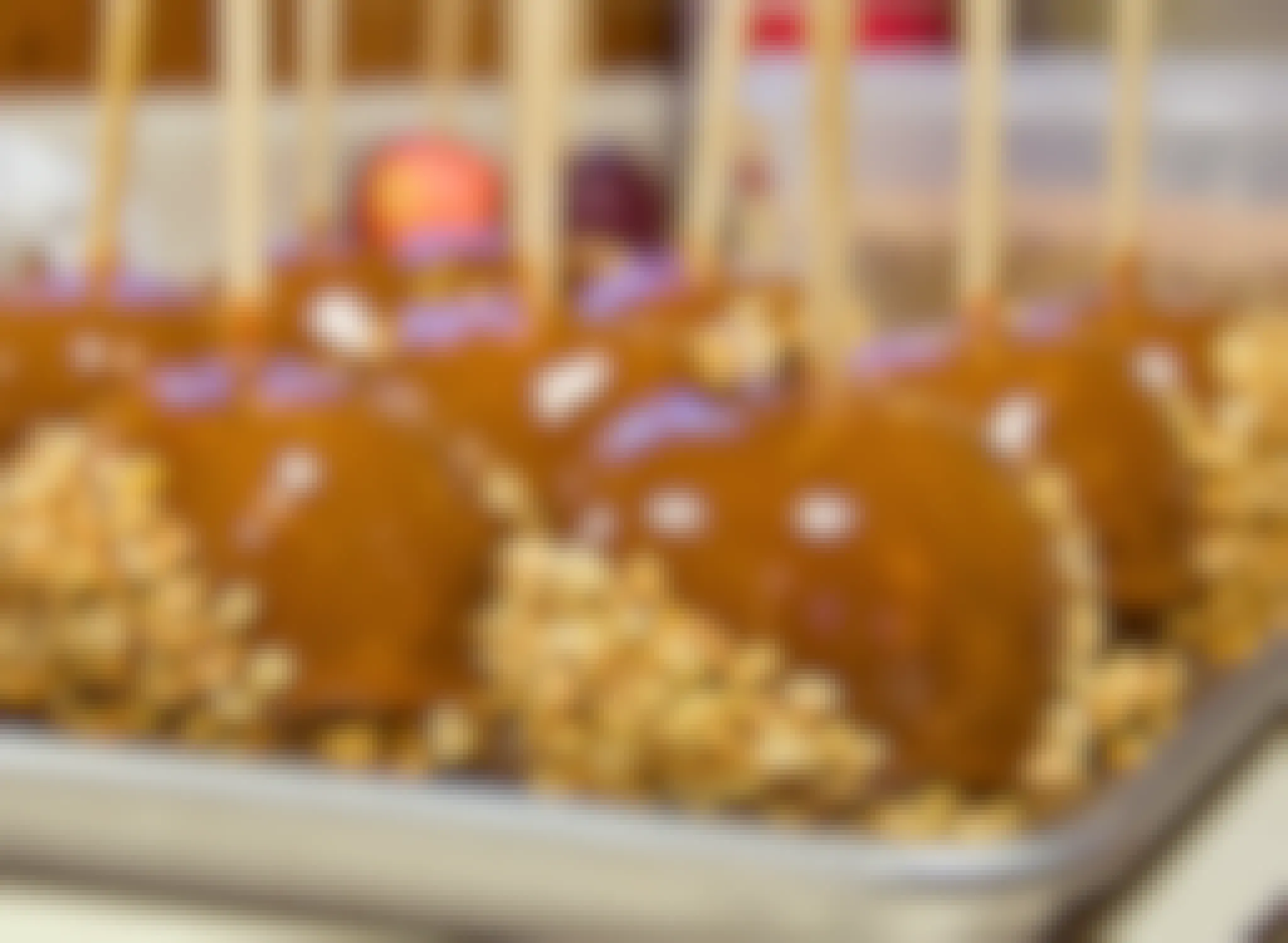 caramel apples dipped in nuts on baking sheet