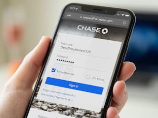 A close-up of someone holding an iPhone displaying the Chase Bank online banking log in screen with the username typed in as "DeadPresidentsClub