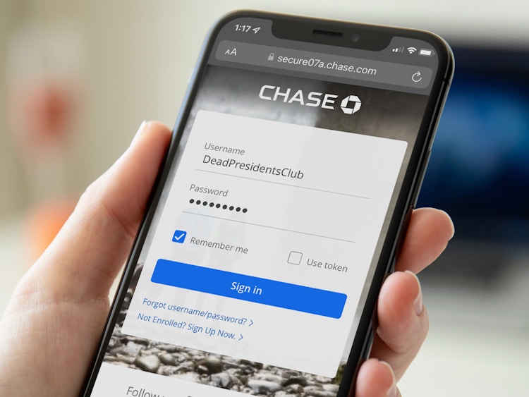 A close-up of someone holding an iPhone displaying the Chase Bank online banking log in screen with the username typed in as "DeadPresidentsClub