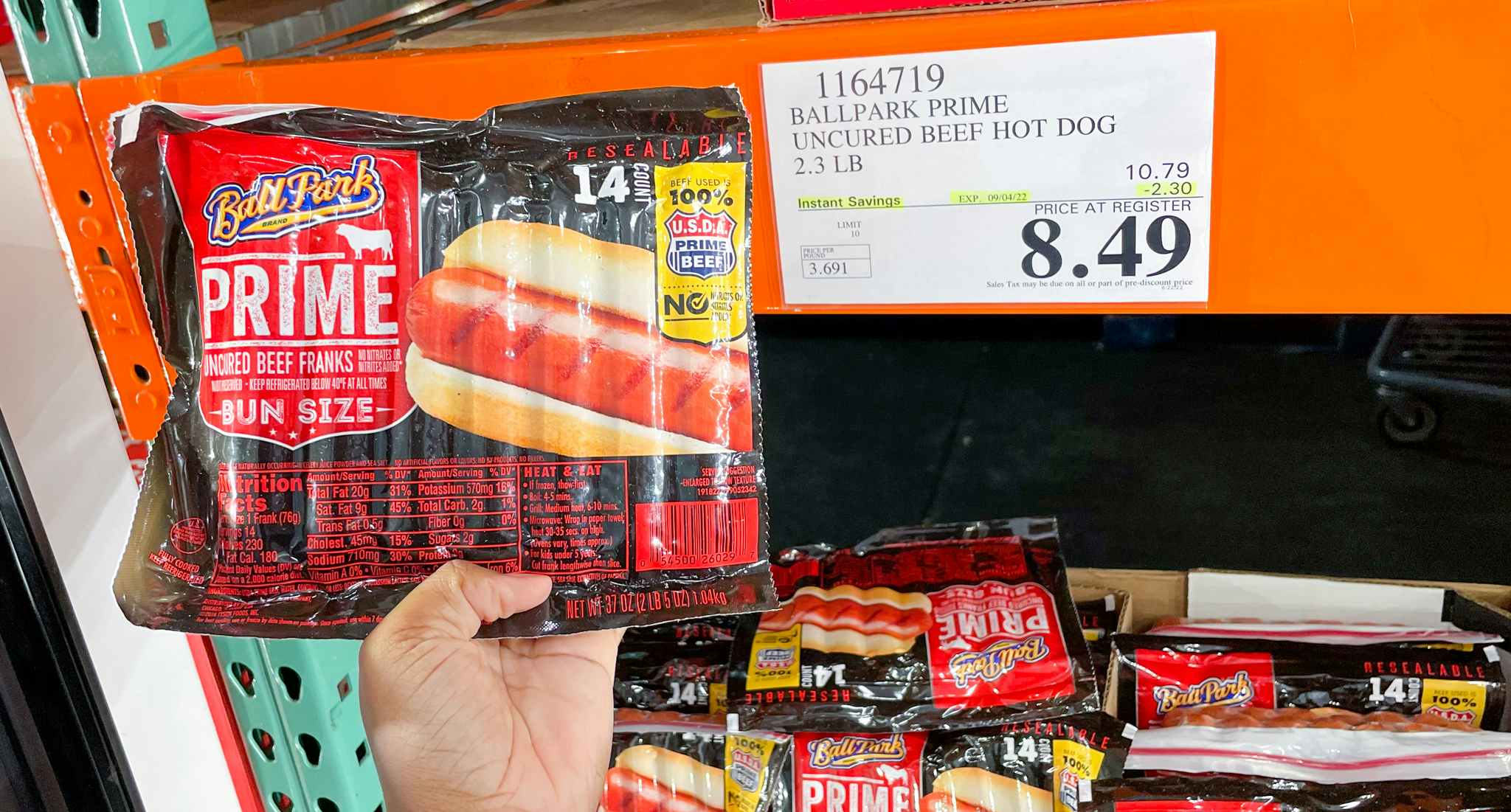 hand held hot dogs near sale sign at costco