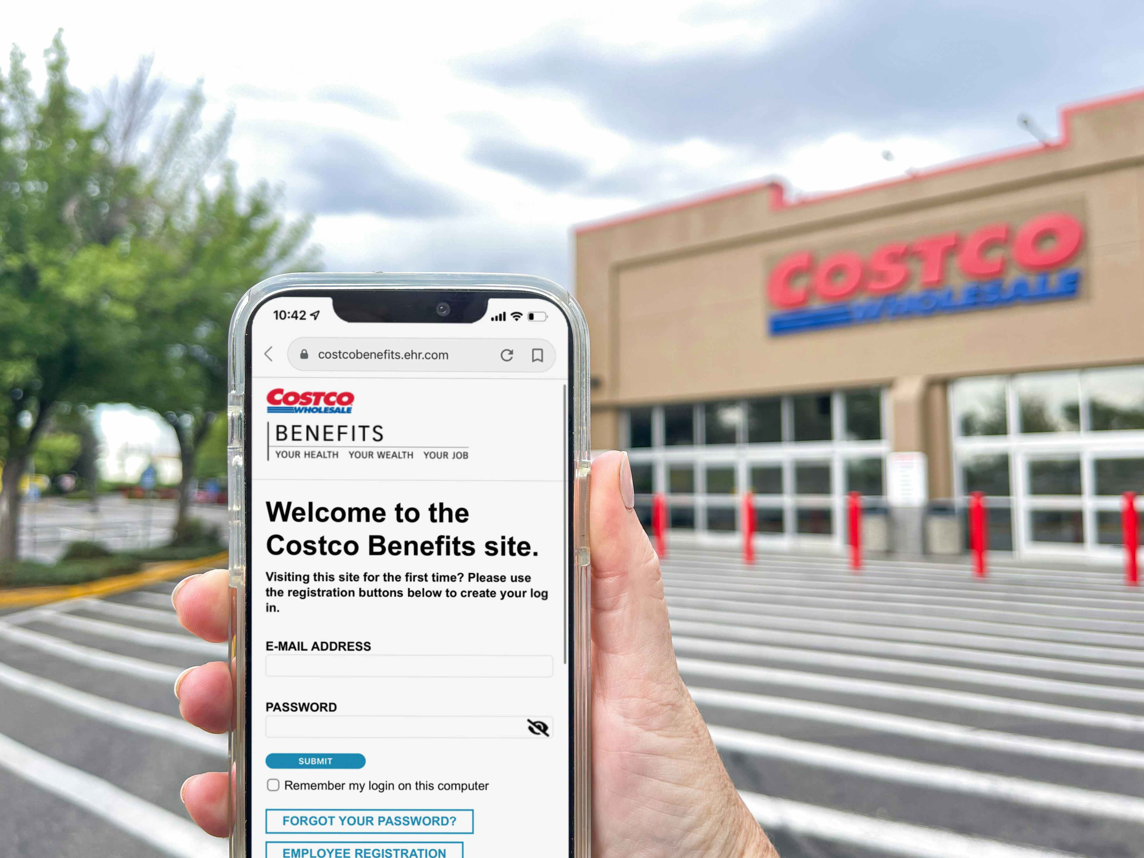 a person holding a cellphone with costco benifits on screen in front of costco 