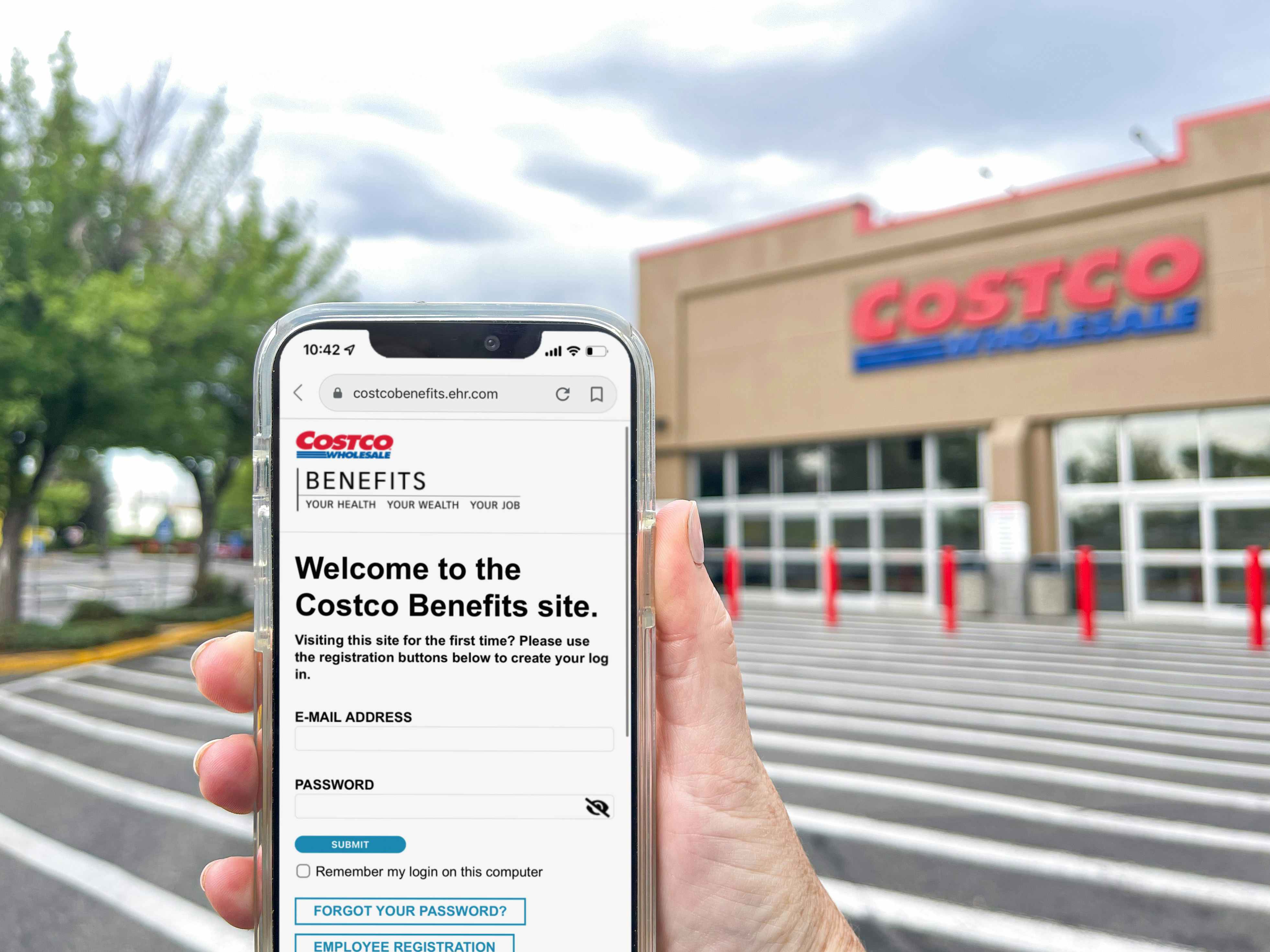 a person holding a cellphone with costco benifits on screen in front of costco