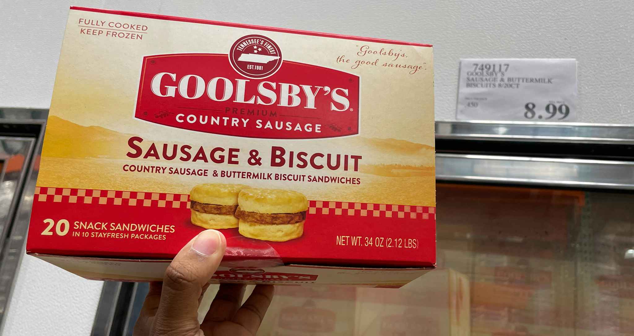sausage biscuits in a box hand held near sale sign at costco