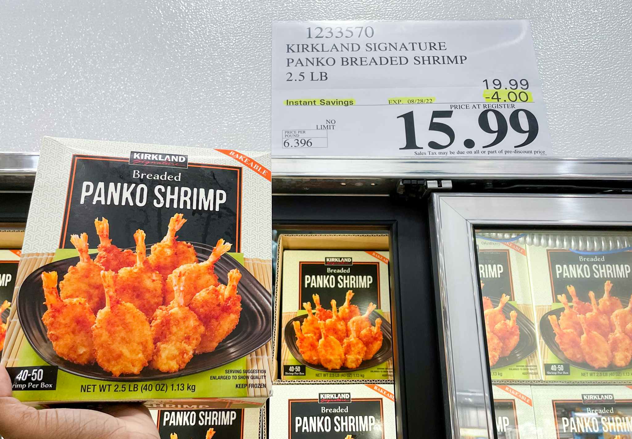 breaded shrimp in a box hand held near sale sign at costco