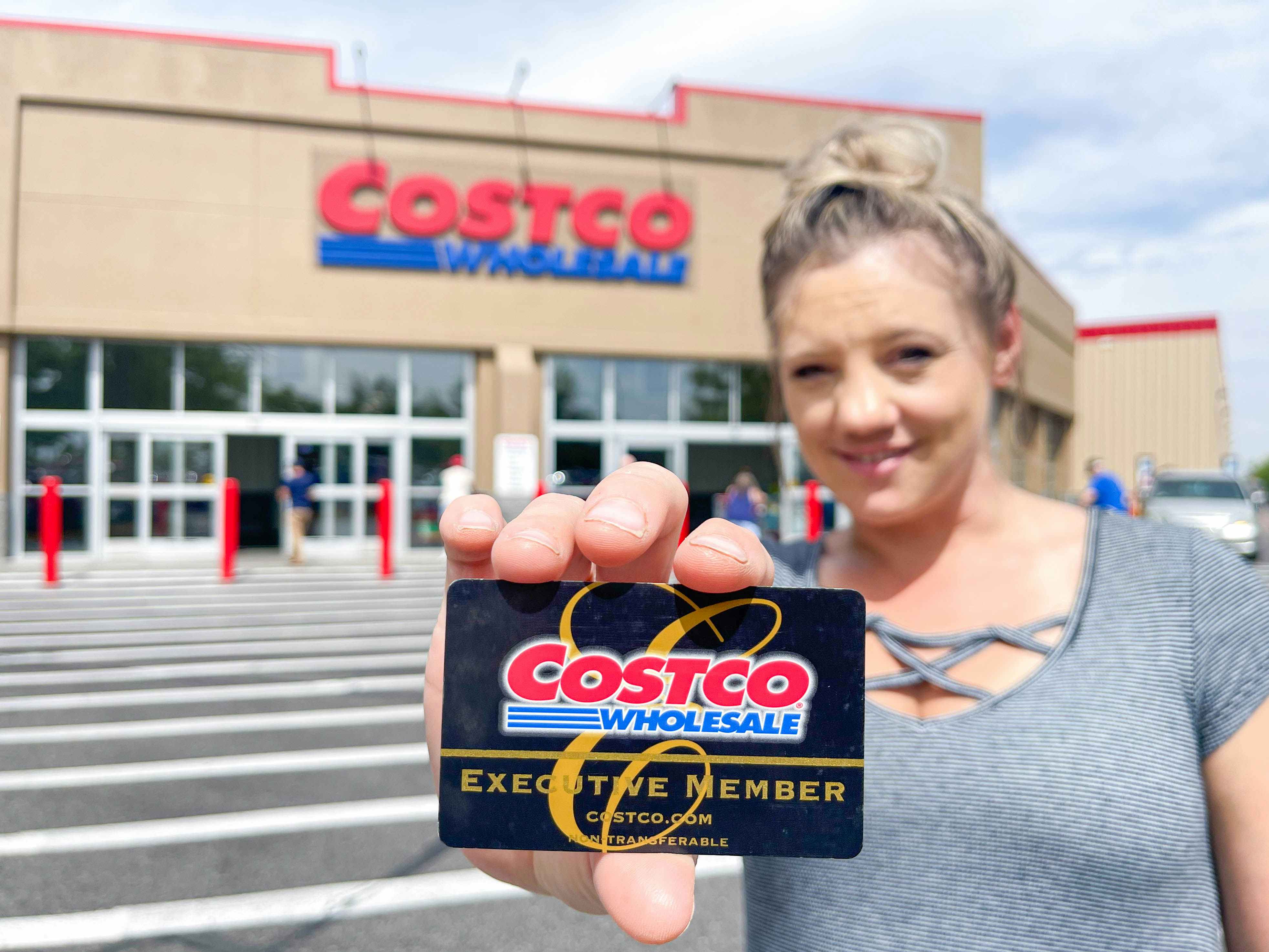 a woman holding a costco membership card in front of costco 