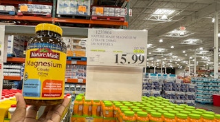 vitamin hand held near sale sign at costco