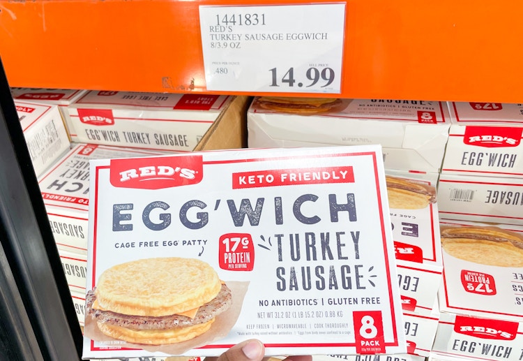 breakfast snadwich hand held near sale sign at costco