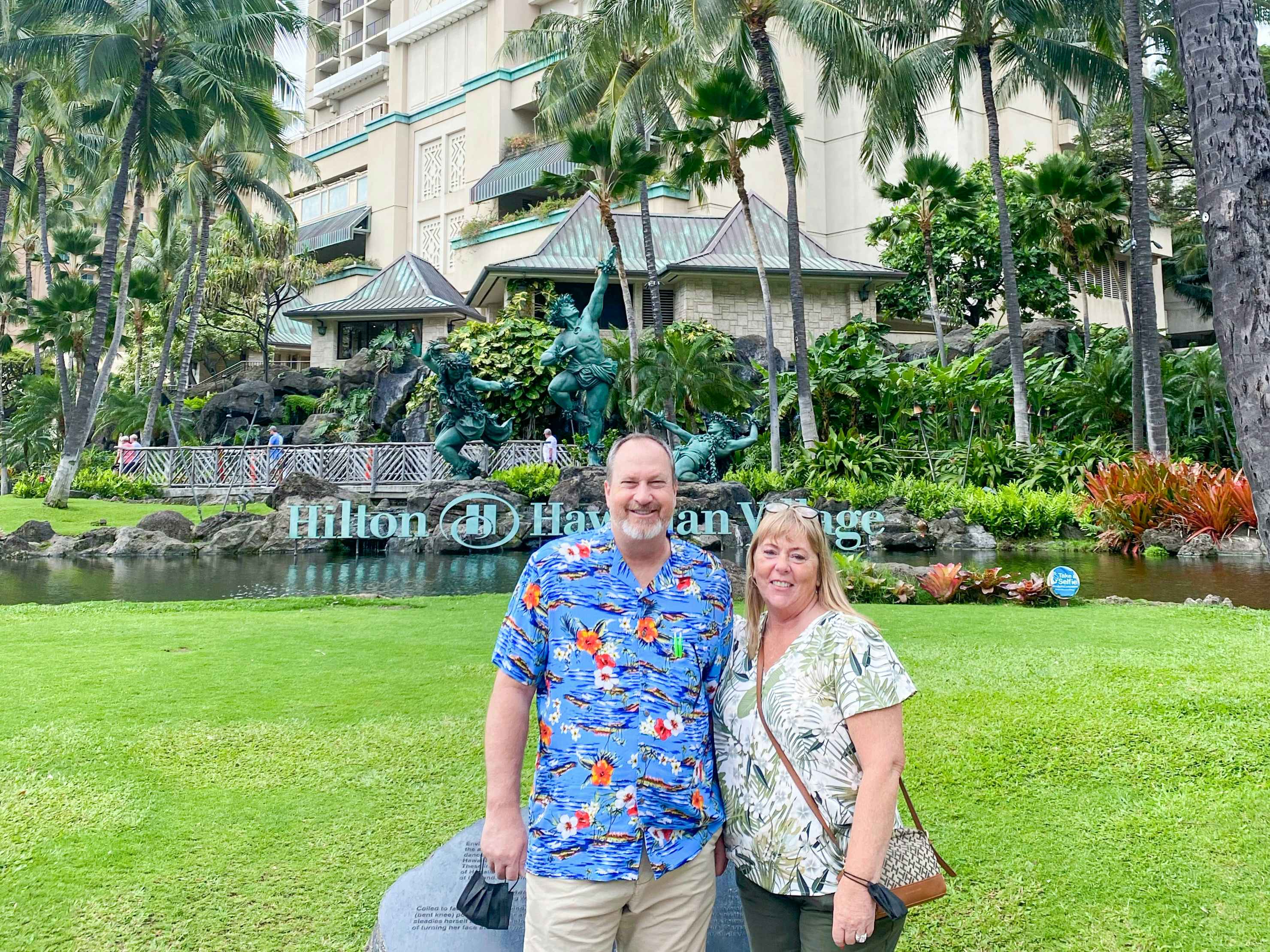 a couple standing in from of the hilton hotel in hawaii