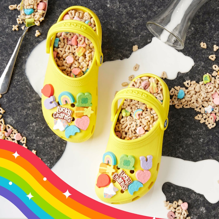 pair of yellow crocs with lucky charm cereal inside the crocs and milk spilt with lucky charm jibbitz on the croc
