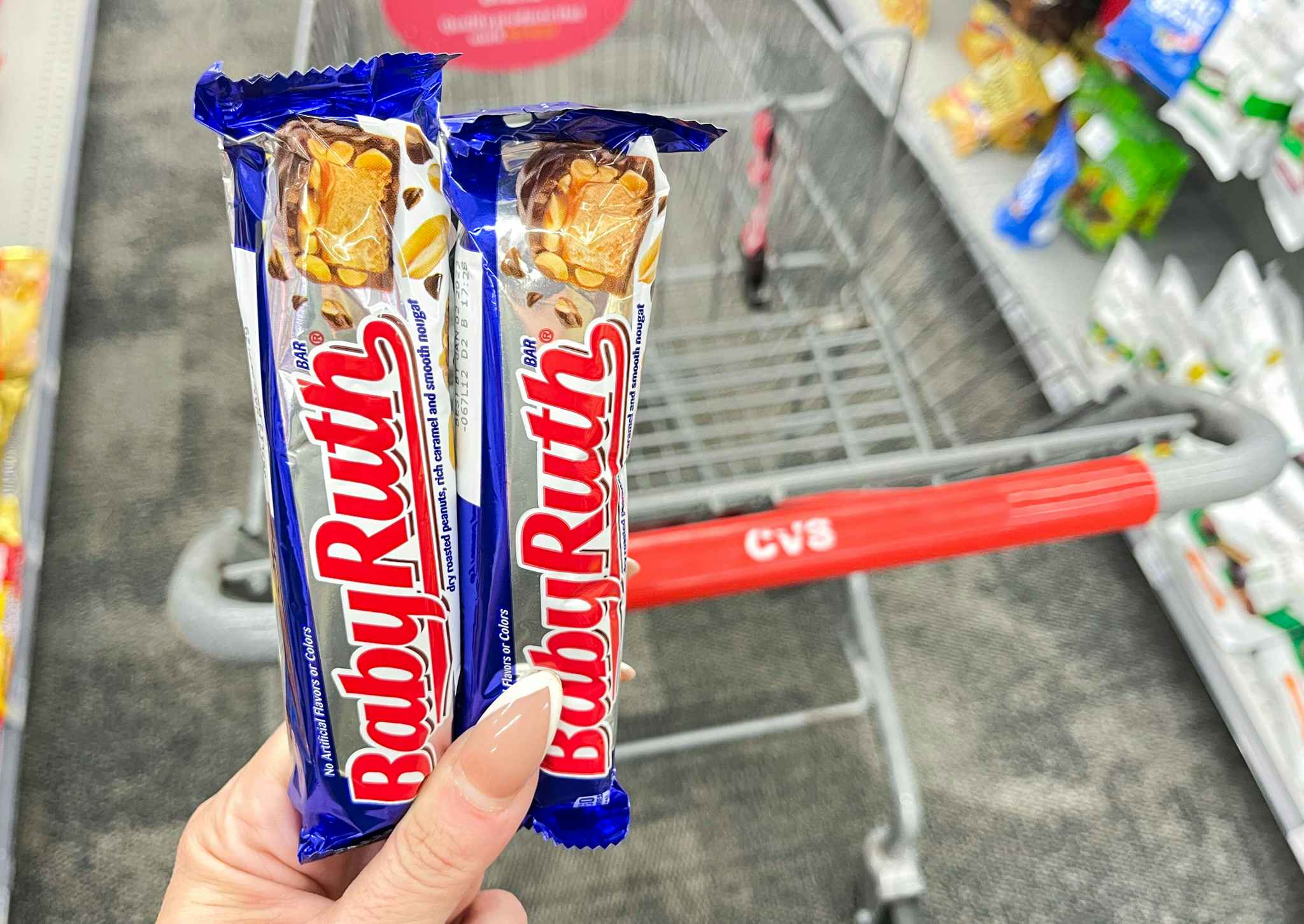 two baby ruth candy bars held in front of cvs shopping cart