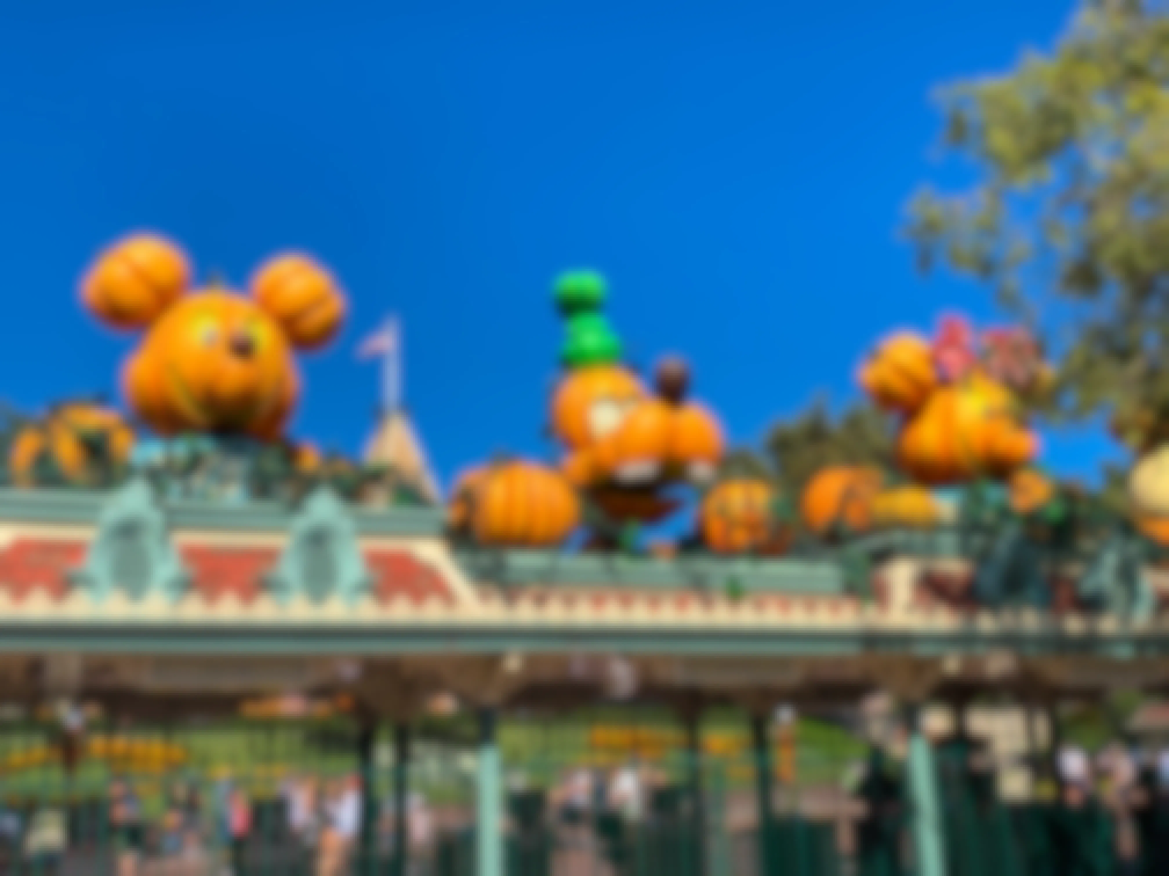 A Disney park with Halloween pumpkins made to look like Mickey, Minnie, and Goofy, over the entrance.