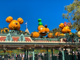A Disney park with Halloween pumpkins made to look like Mickey, Minnie, and Goofy, over the entrance.