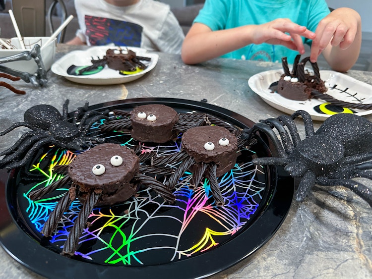 spider cakes on a tray with kids in the background making their own 