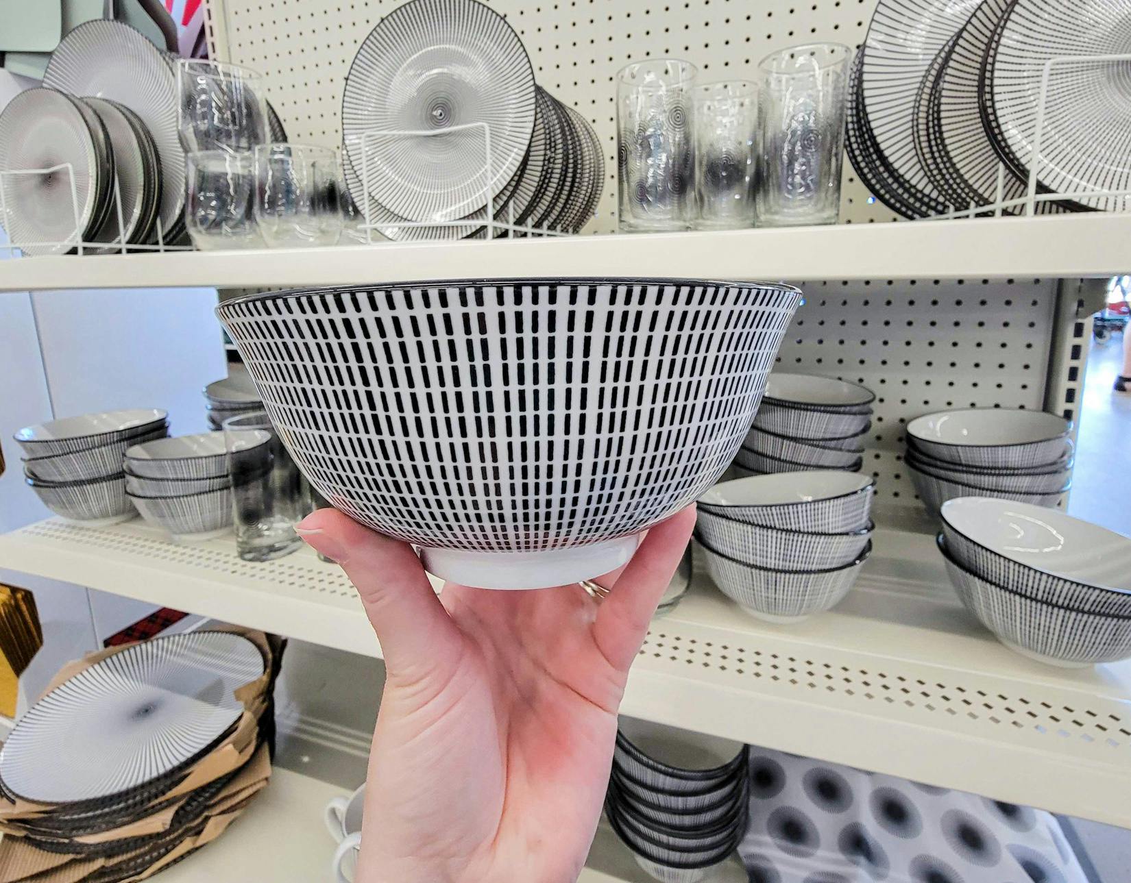 hand holding a white bowl with short black lines on it in a pattern
