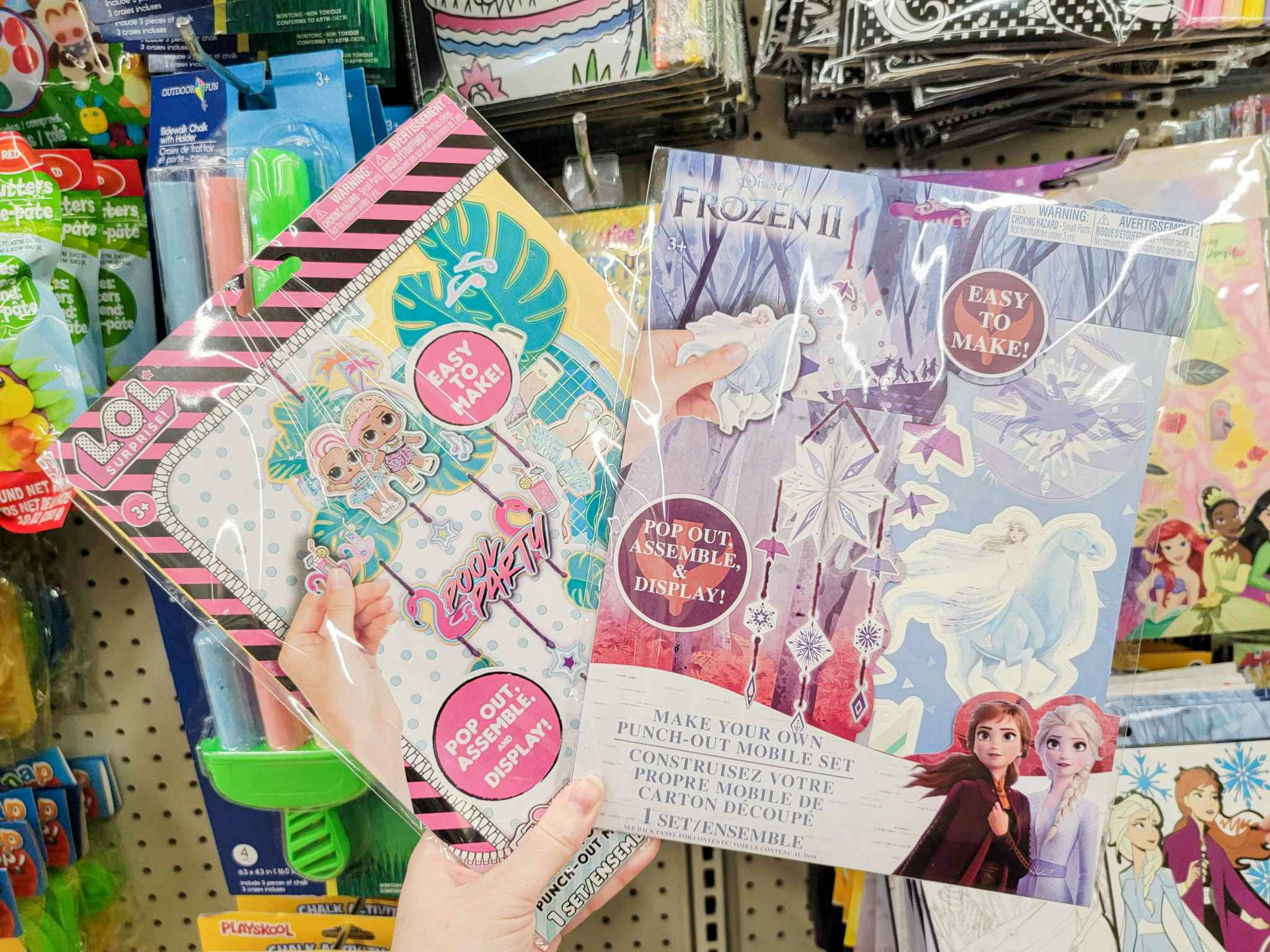 hand holding 2 make your own mobile craft kits, lol surprise and disney frozen