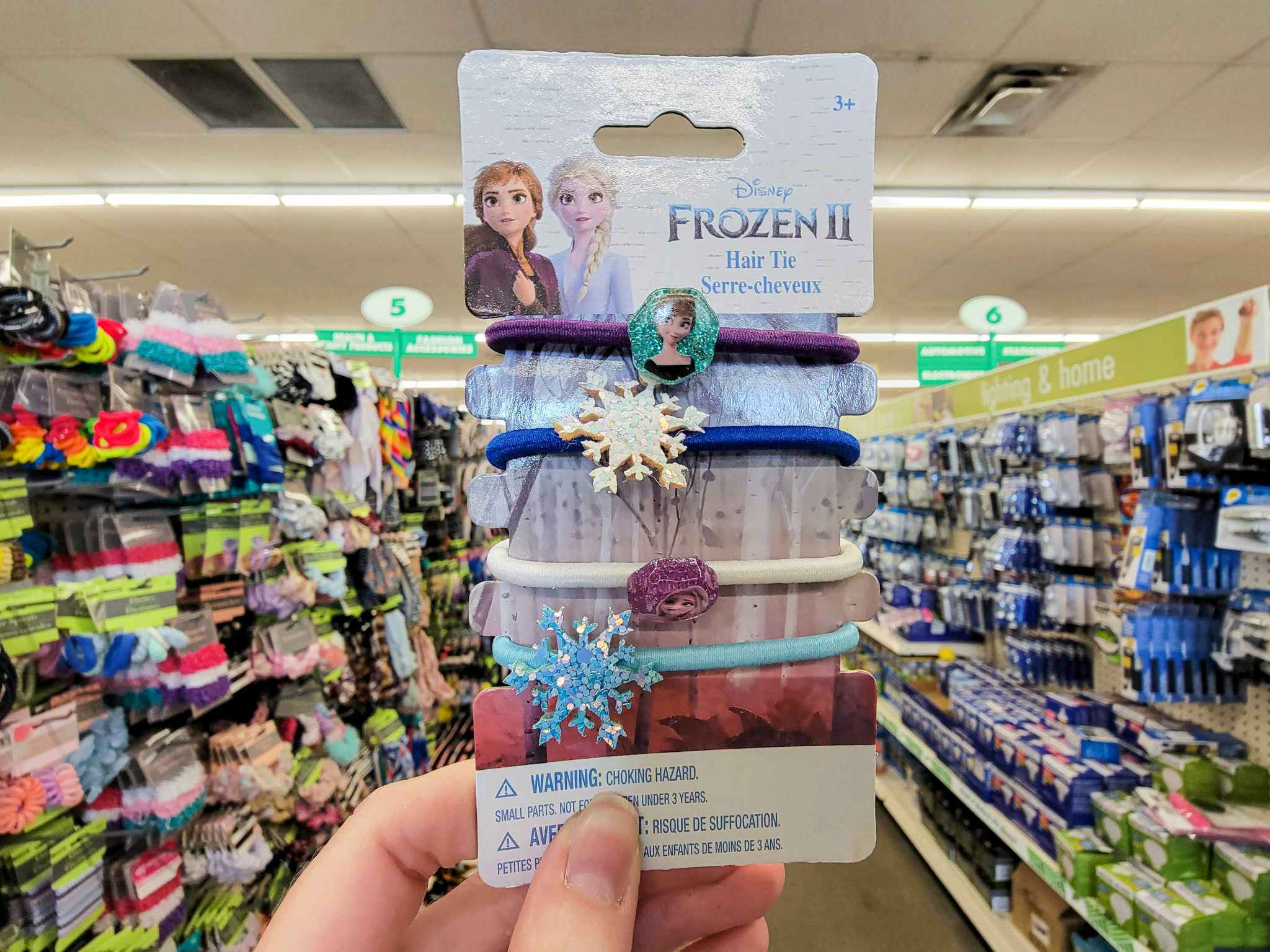 hand holding a pack of disney frozen hair ties with character decals on them