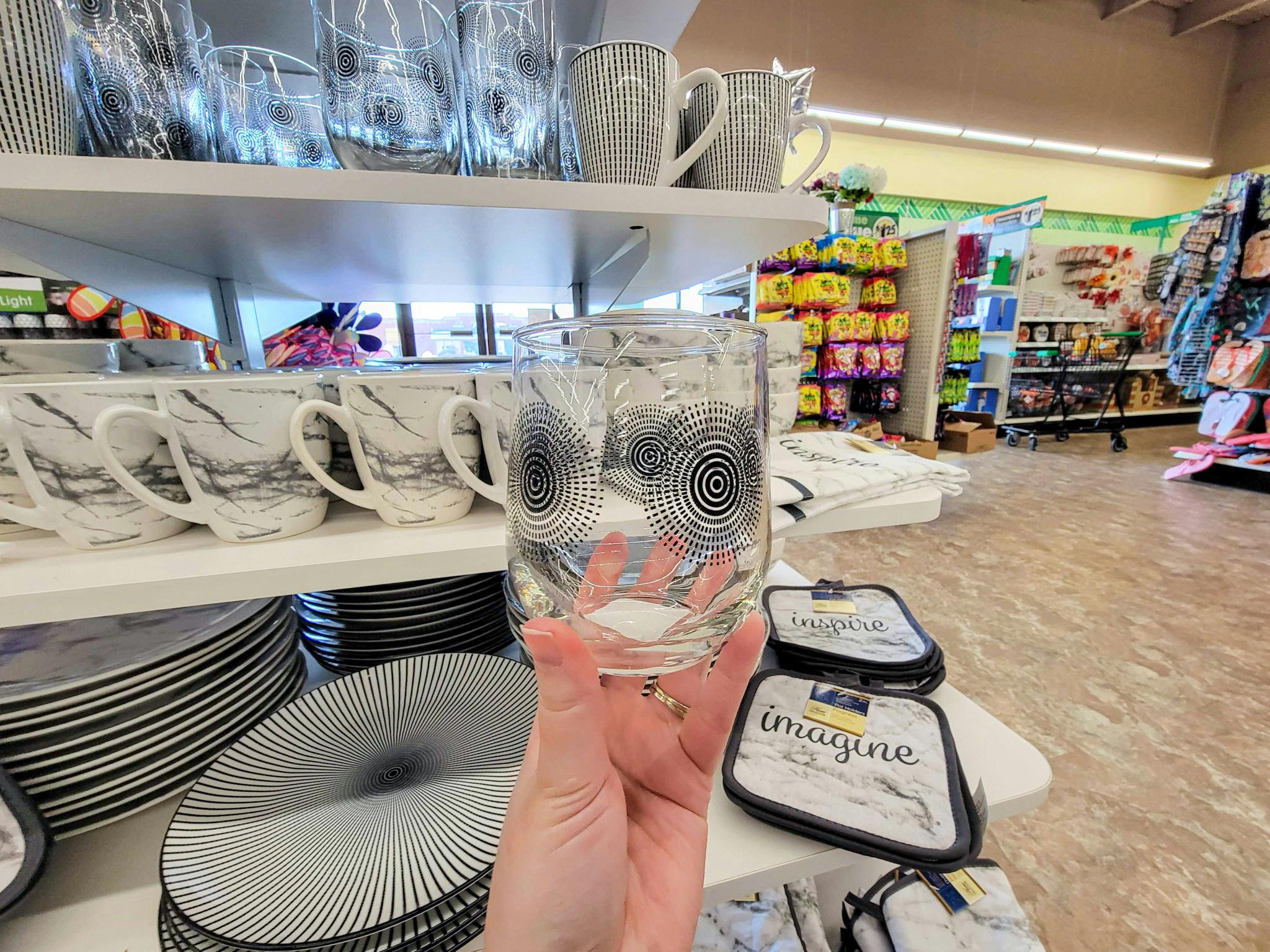 hand holding a short glass with a black circle design on it