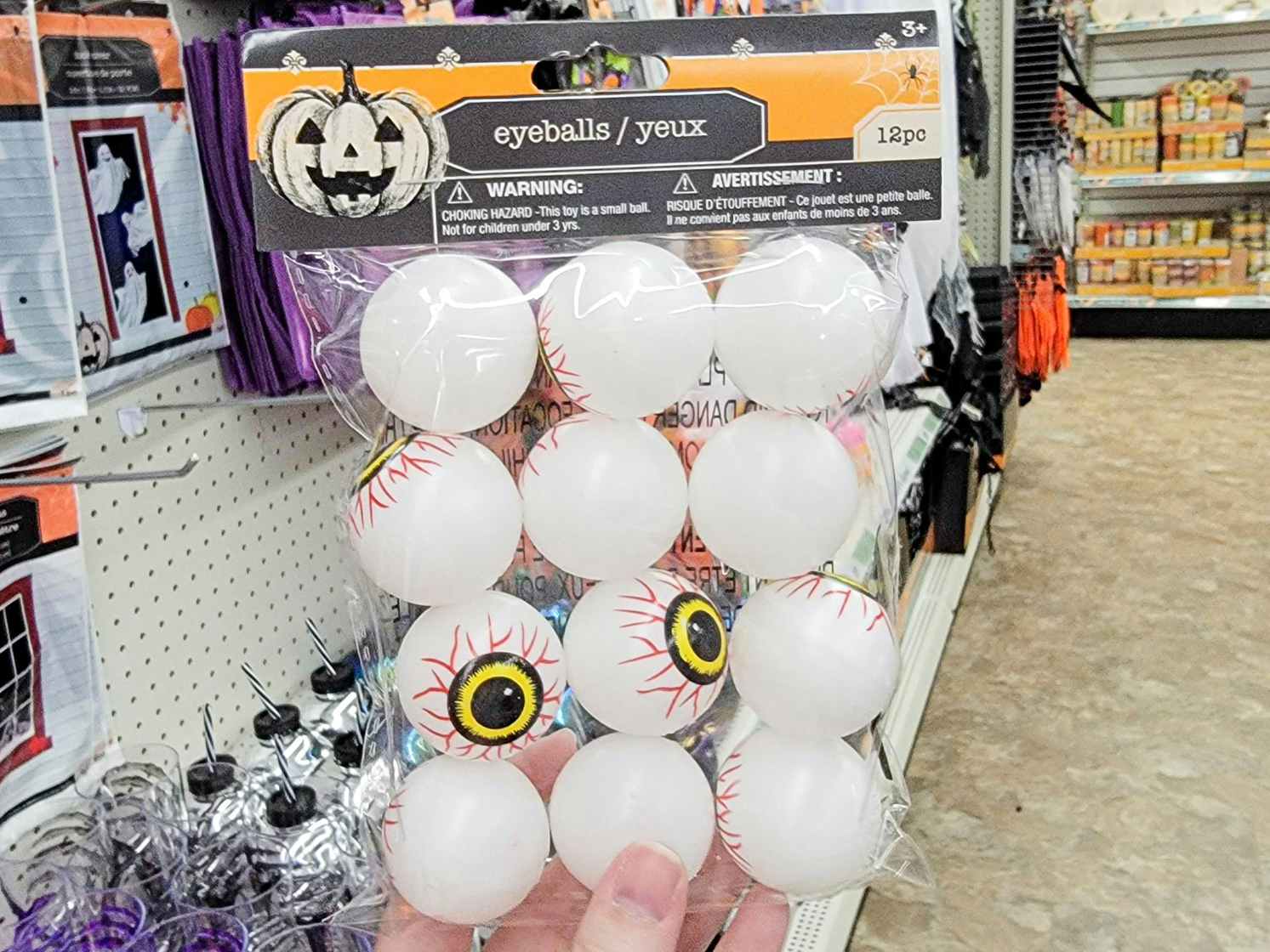 hand holding a pack of 12 eyeballs for halloween party favors