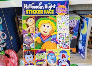 hand holding a kids halloween night sticker face activity book