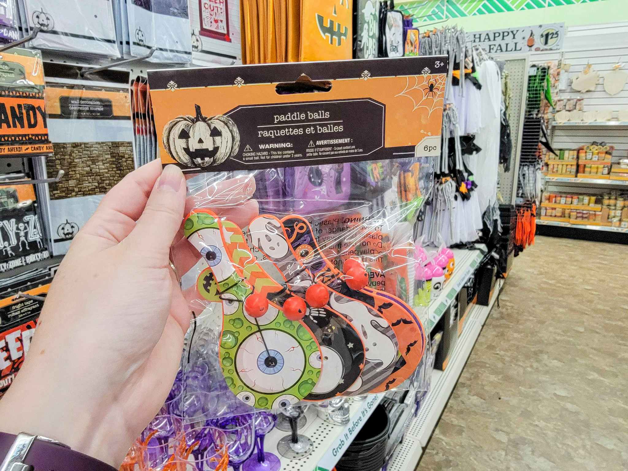 hand holding a pack of halloween paddle ball toys