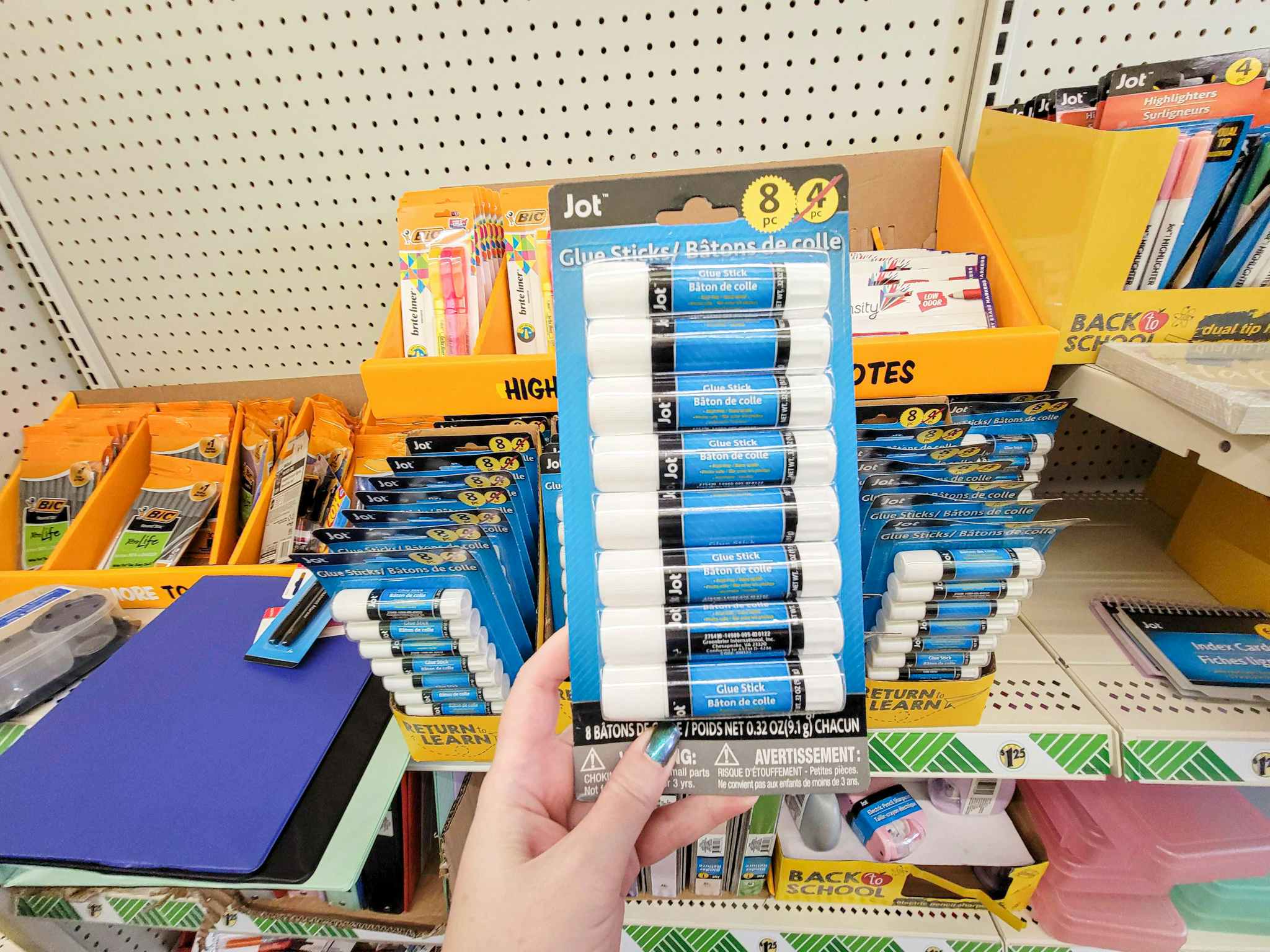 hand holding an 8 pack of jot brand glue sticks