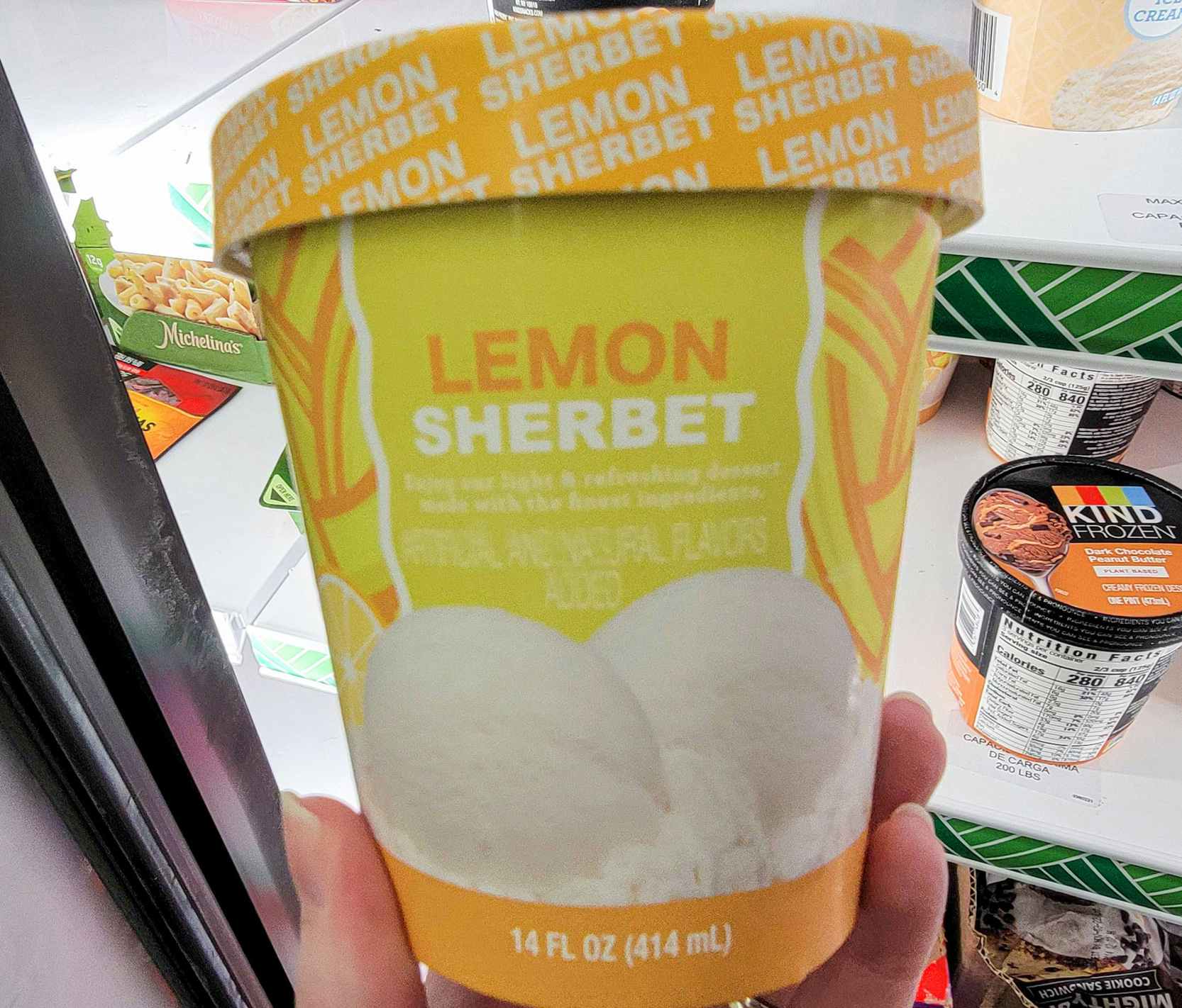 hand holding a container of lemon sherbet