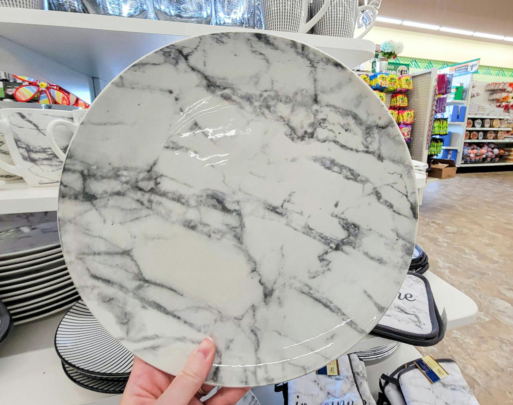 hand holding a dinner plate that is white with grey marbling