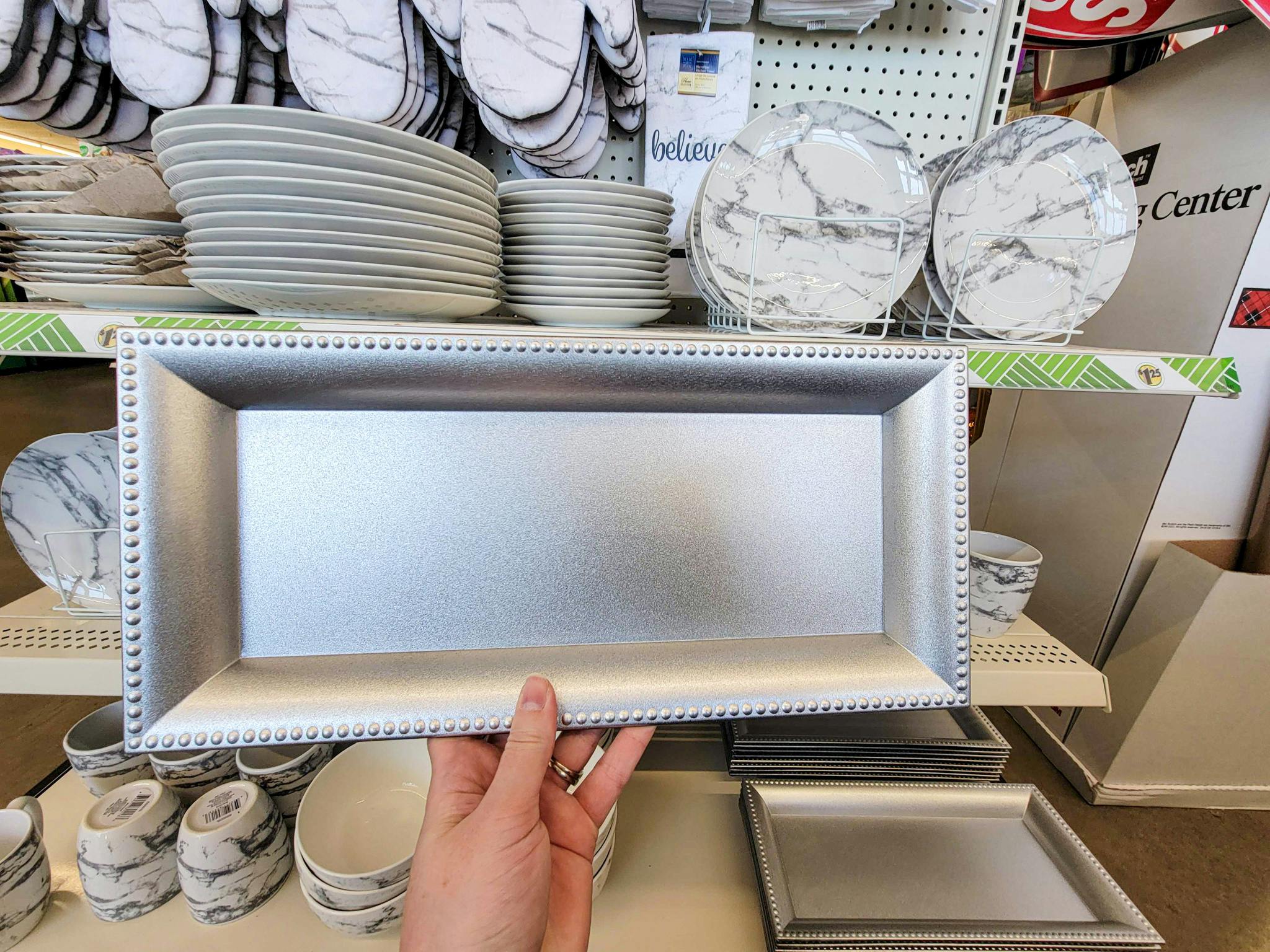 hand holding up a silver rectangular serving tray