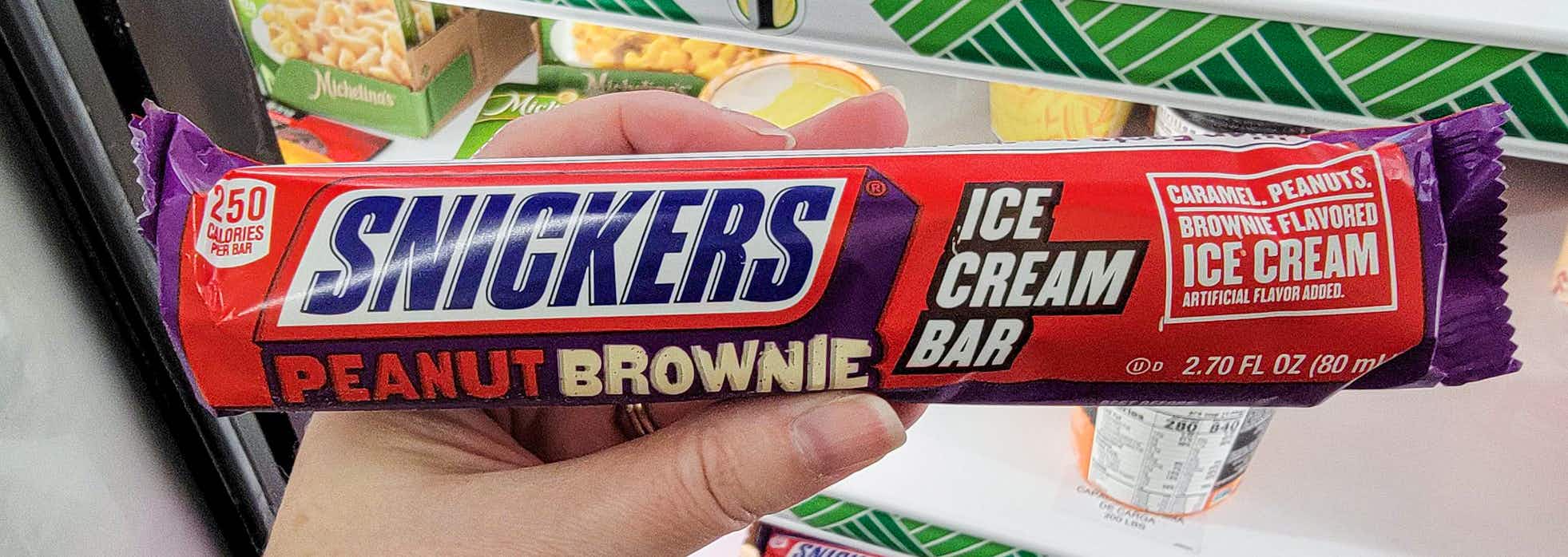 hand holding a peanut butter brownie snickers ice cream bar