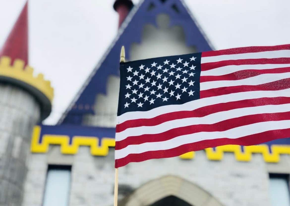 A small American flag being held up in front of a Dutch Wonderland entrance.