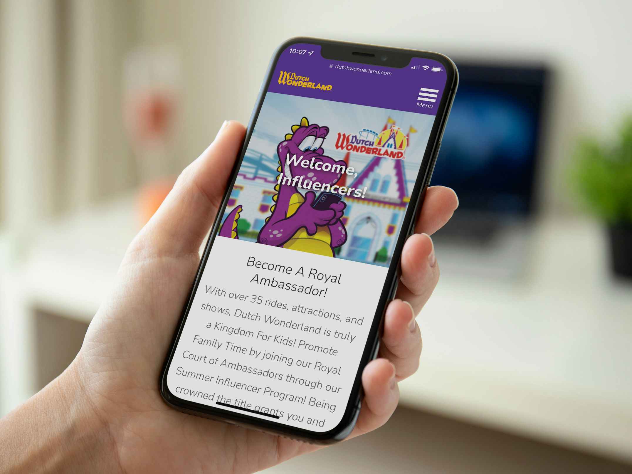 A person's hand holding a cell phone displaying the Dutch Wonderland website's page about their influencer program.