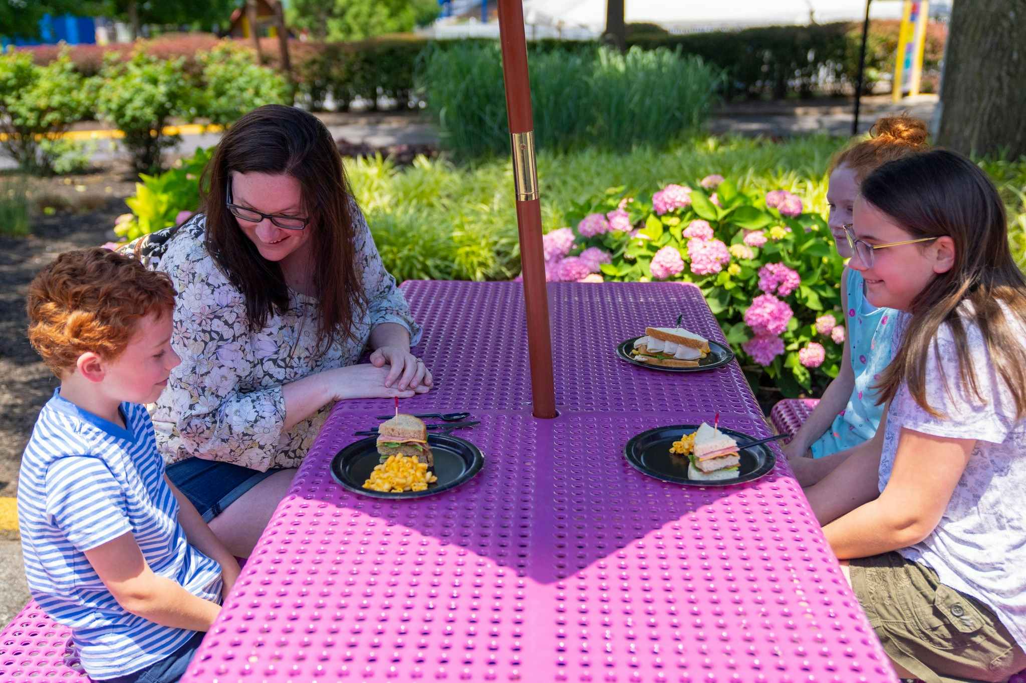 A mom and kids sitting at a picnic table to eat at Dutch Wonderland park.