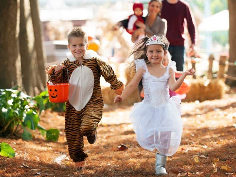 Two children in Halloween costumes running down a path at Dutch Wonderland amusement park