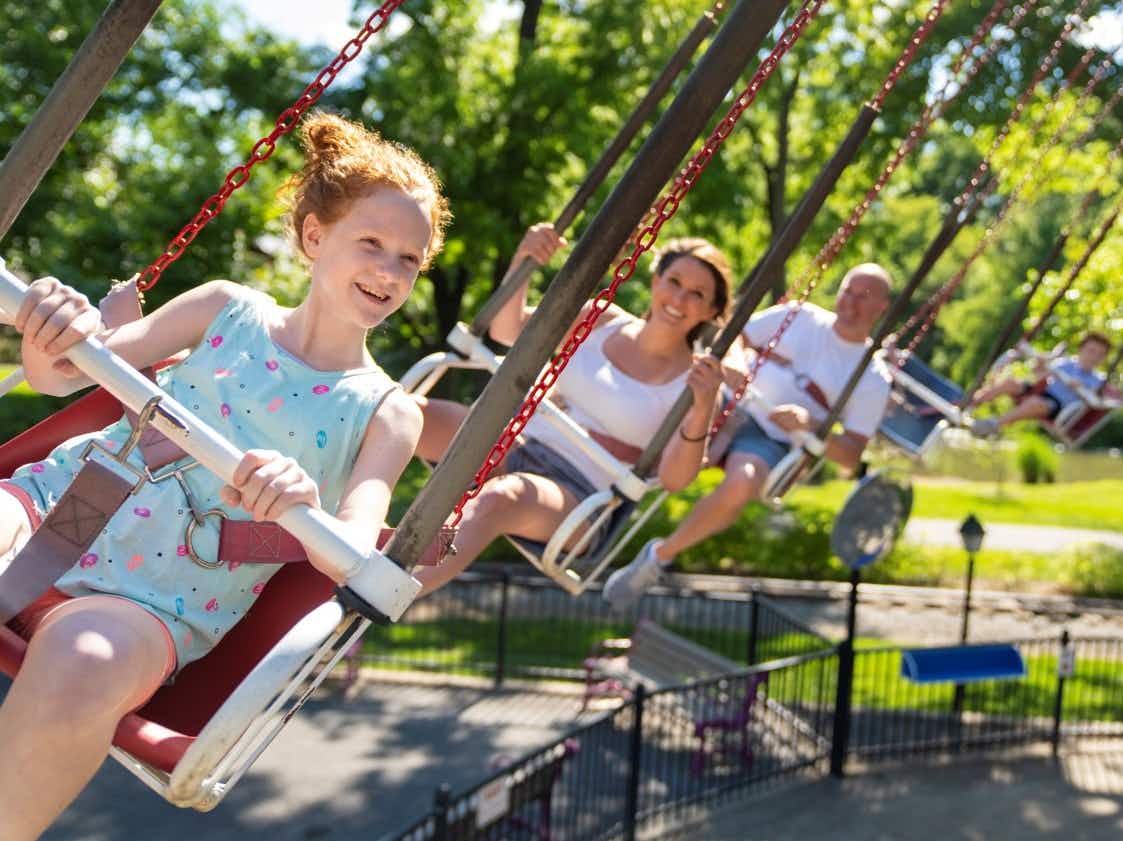 A girl and her family riding a swing ride at Dutch Wonderland.