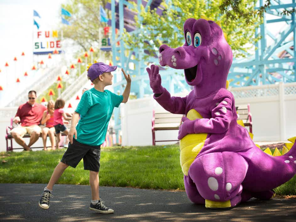 A child giving a high five to a Dutch Wonderland Mascot.