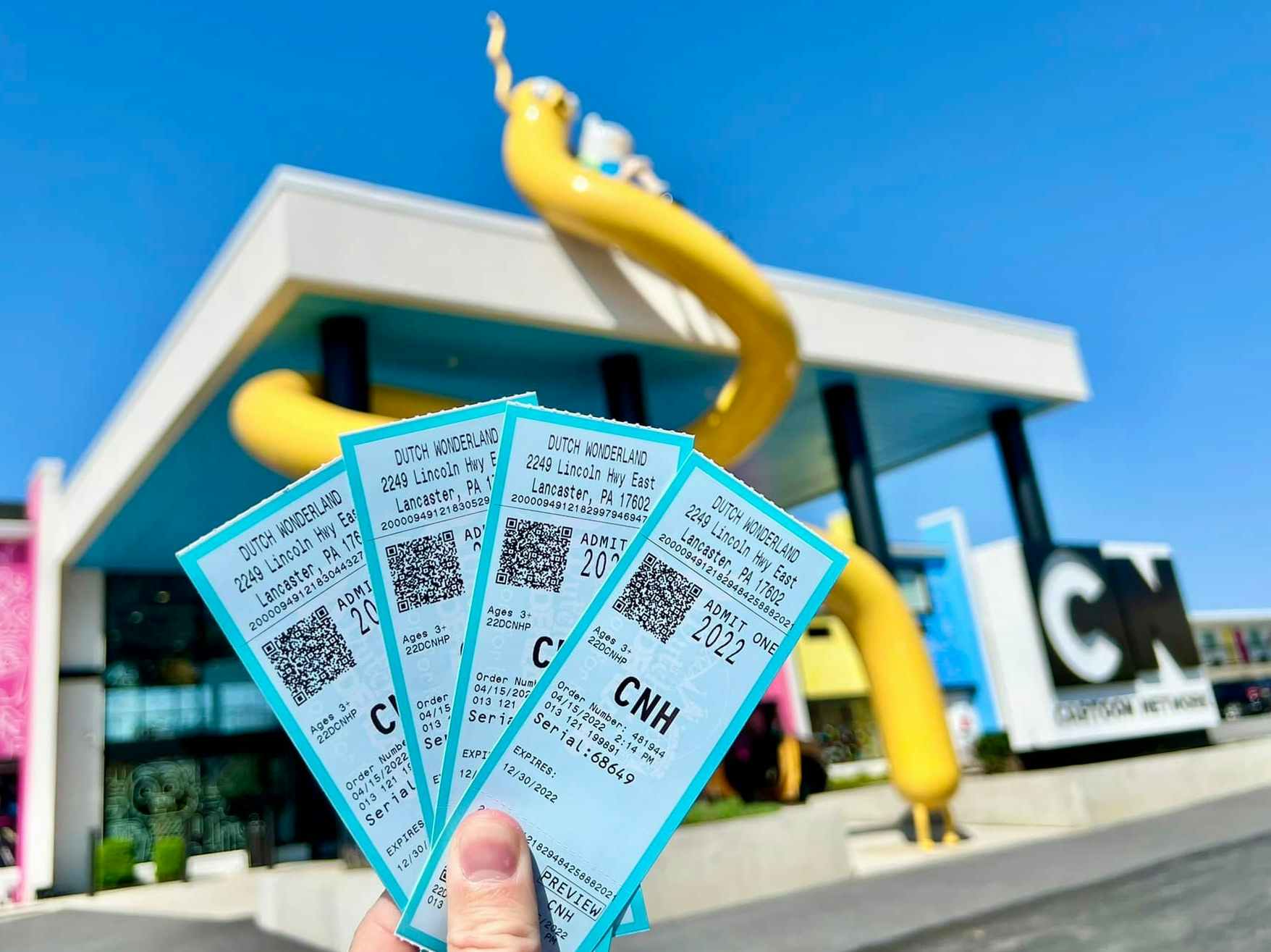 A person holding up Dutch Wonderland tickets in front of the Cartoon Network Hotel in Lancaster Pennsylvania
