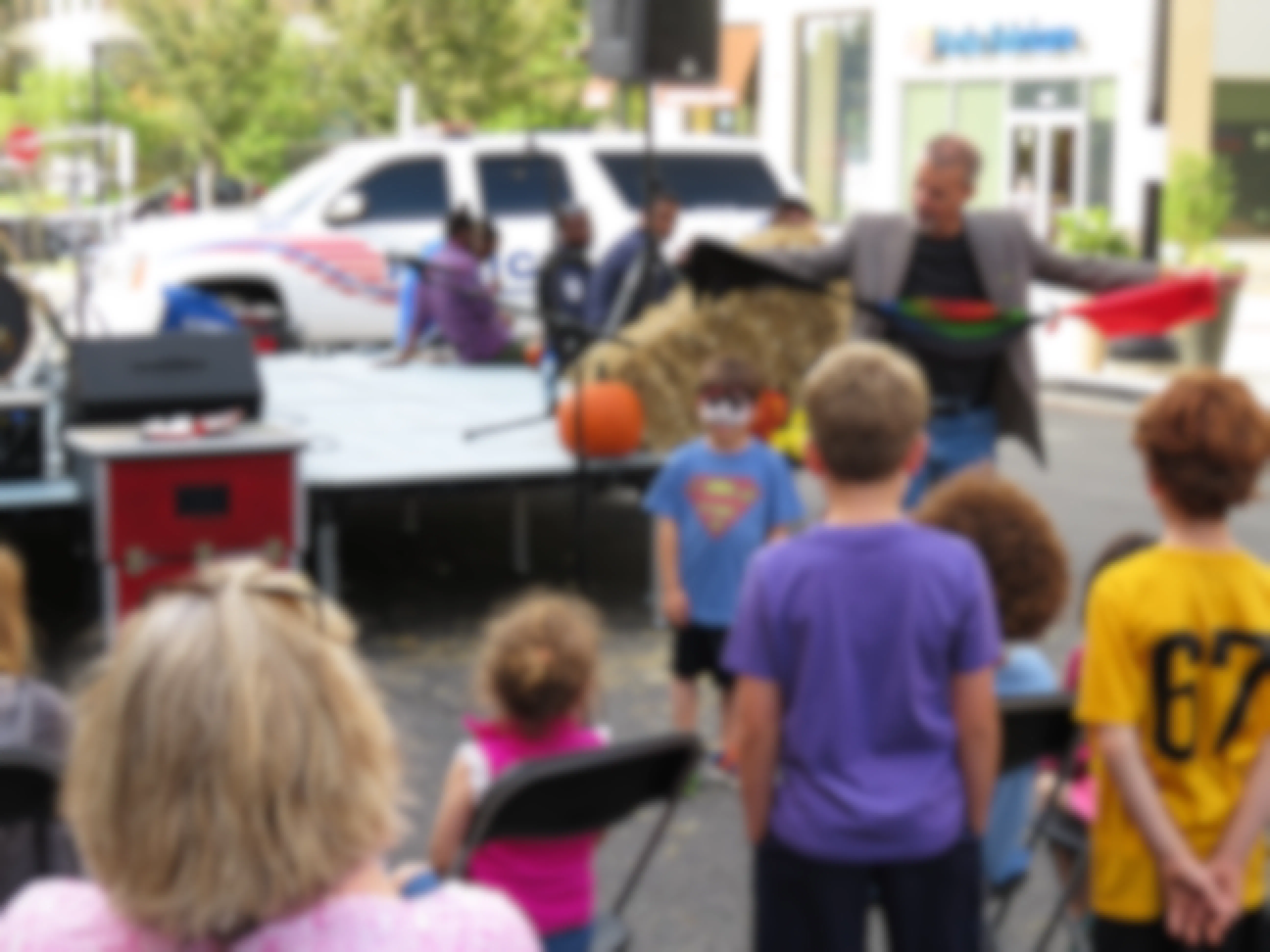 A magician performing a magic trick at a fall festival with children watching.