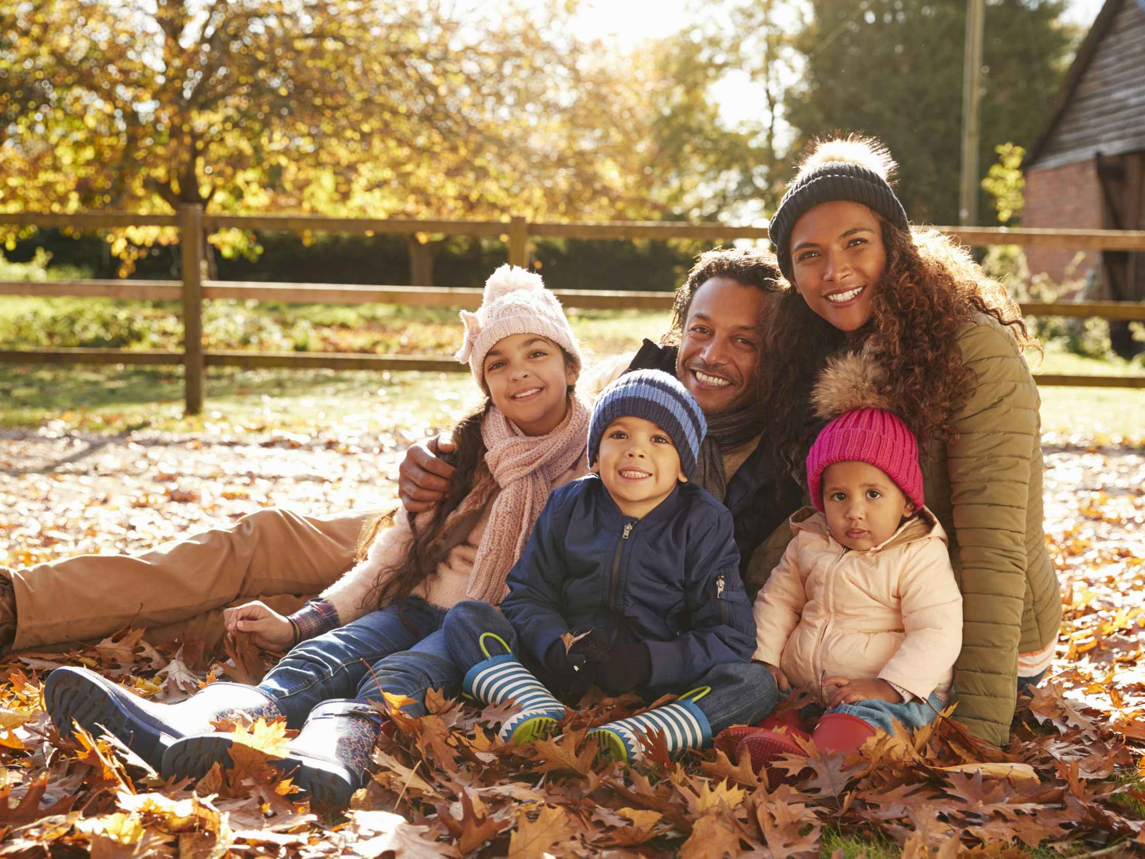 A family dressed for autumn posing together for a portrait in some leaves.
