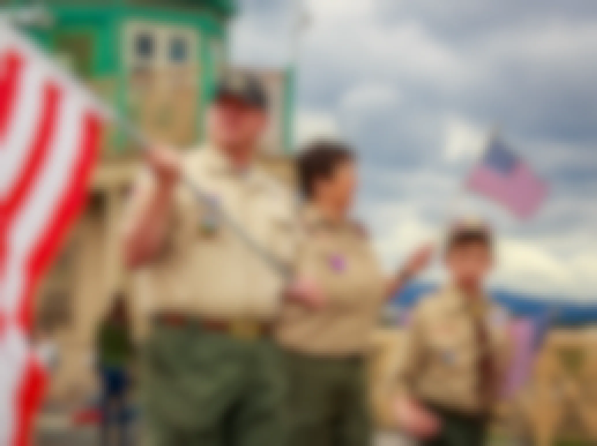 A boy scout troop and leader walking in a parade with American flags.