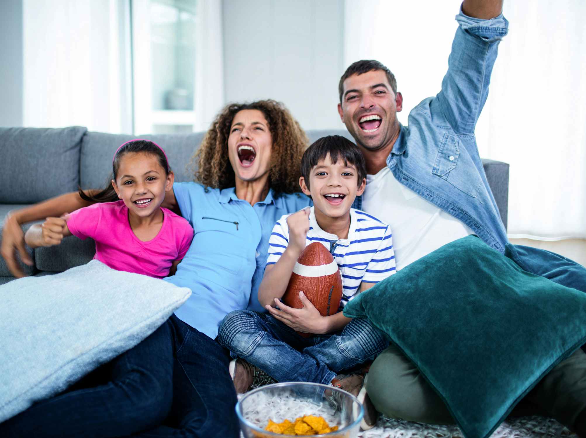young family sitting on couch watching football